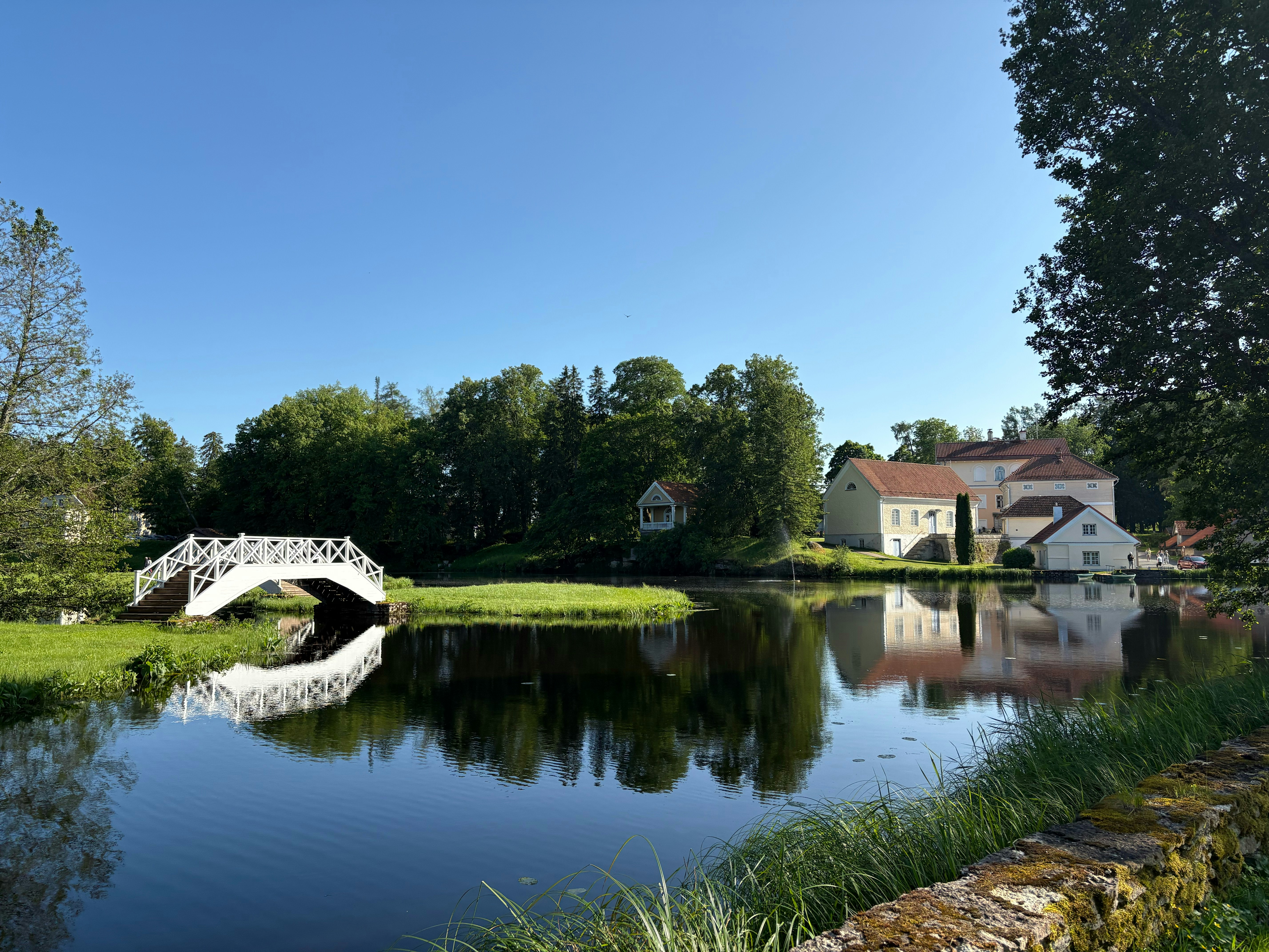Un estanque y un puente se reflejan en aguas tranquilas.