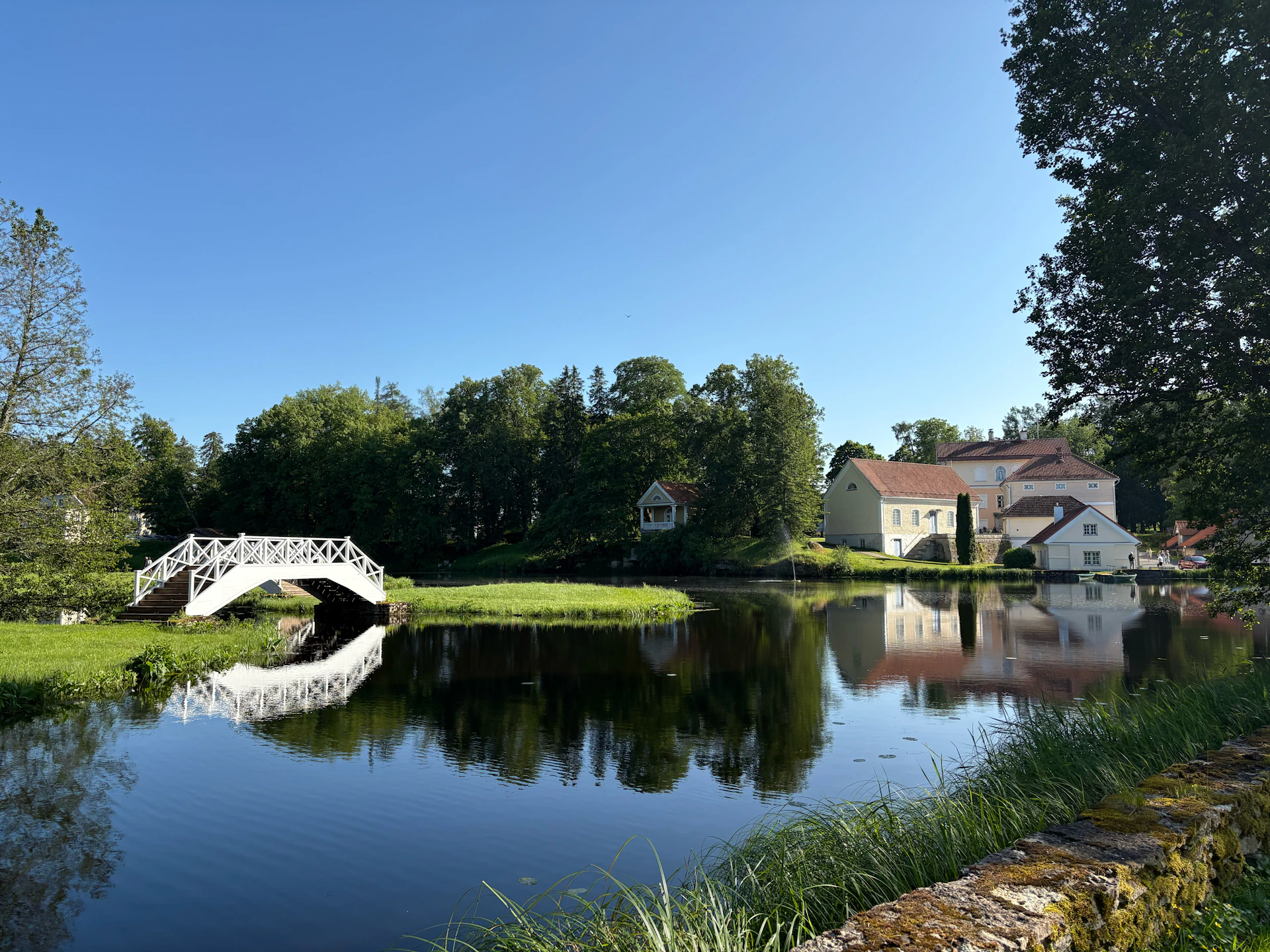 A pond and a bridge reflect in still waters.