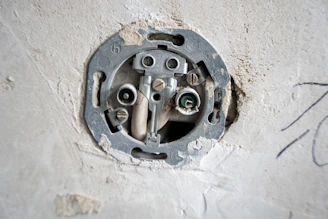 An electrical socket is exposed in a wall.