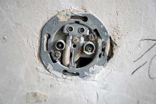 An electrical socket is exposed in a wall.