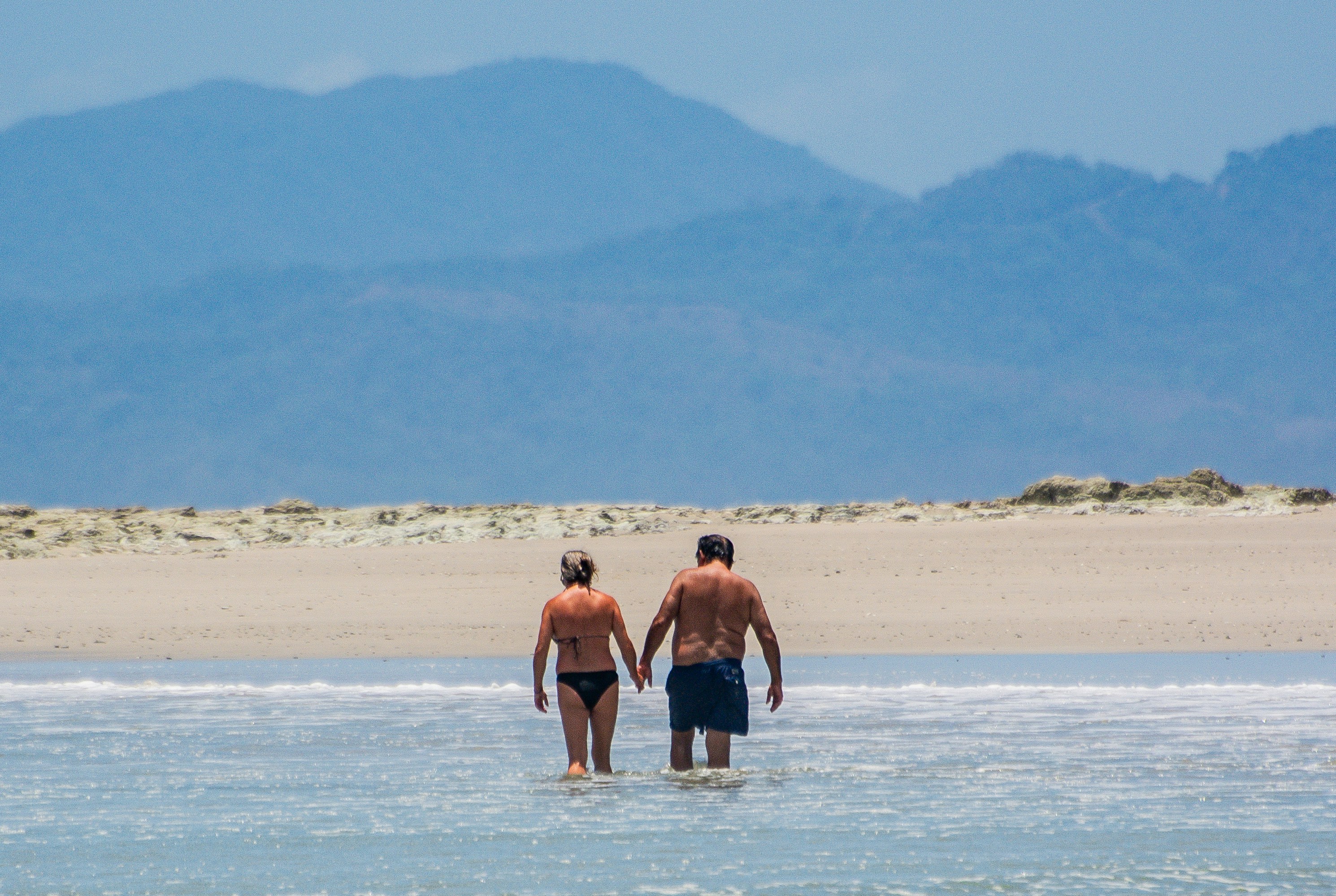 Couple walks hand-in-hand in the ocean.