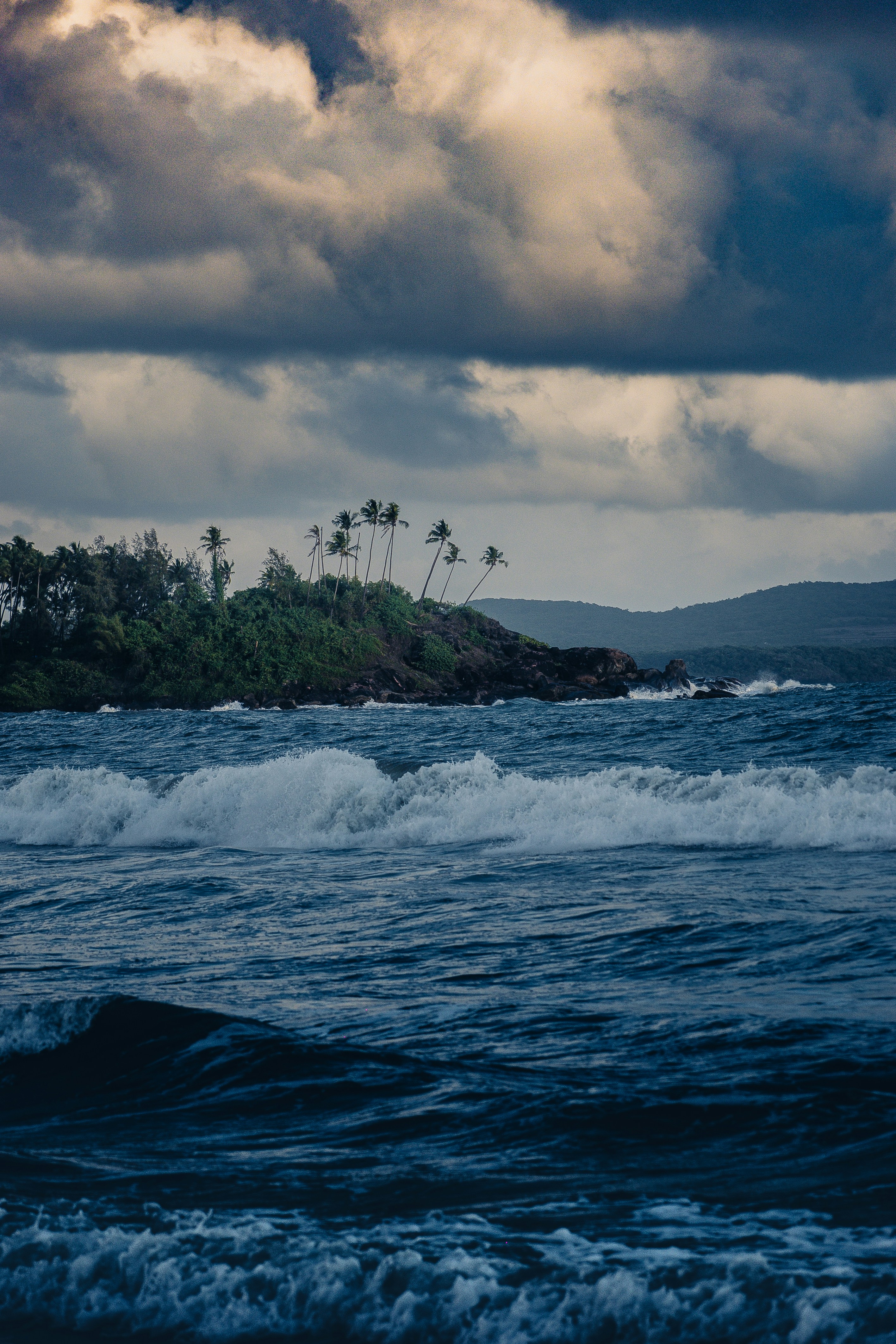Waves crash on a shore under a cloudy sky.