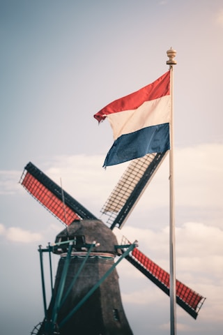 Dutch flag waving near a windmill.