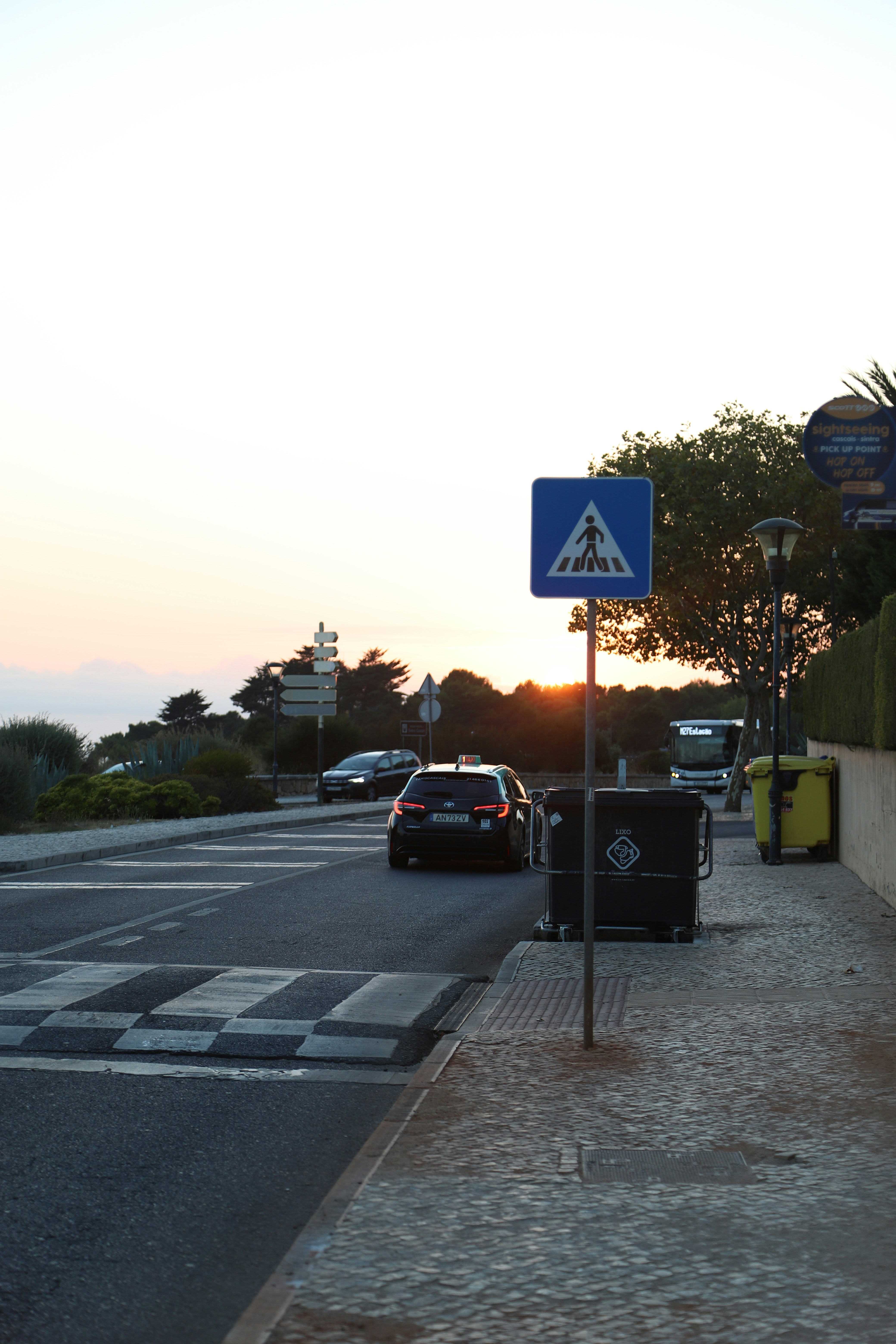 Cars drive on a road near a crosswalk.