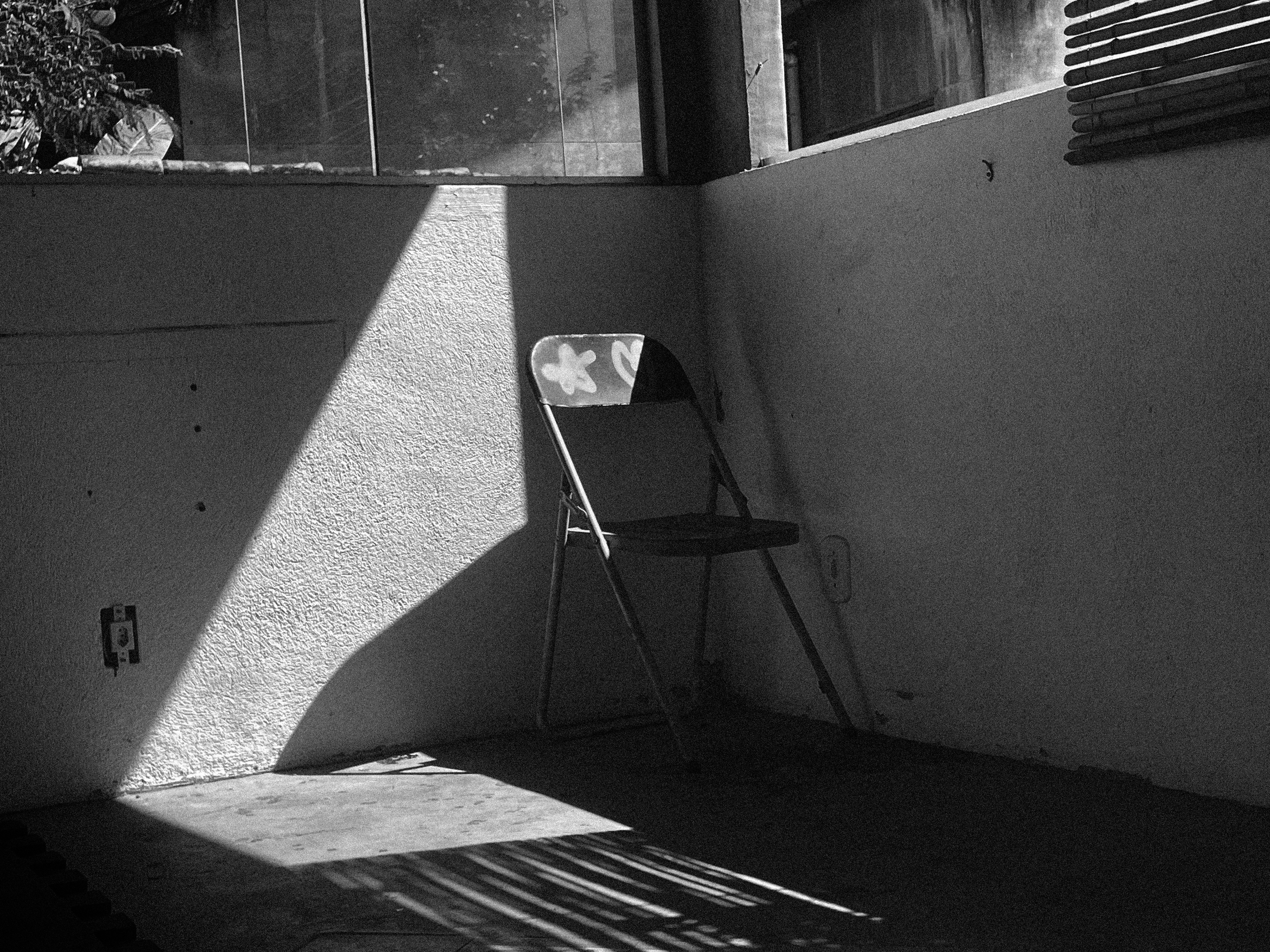 Des ombres tombent sur une chaise dans une pièce vide.