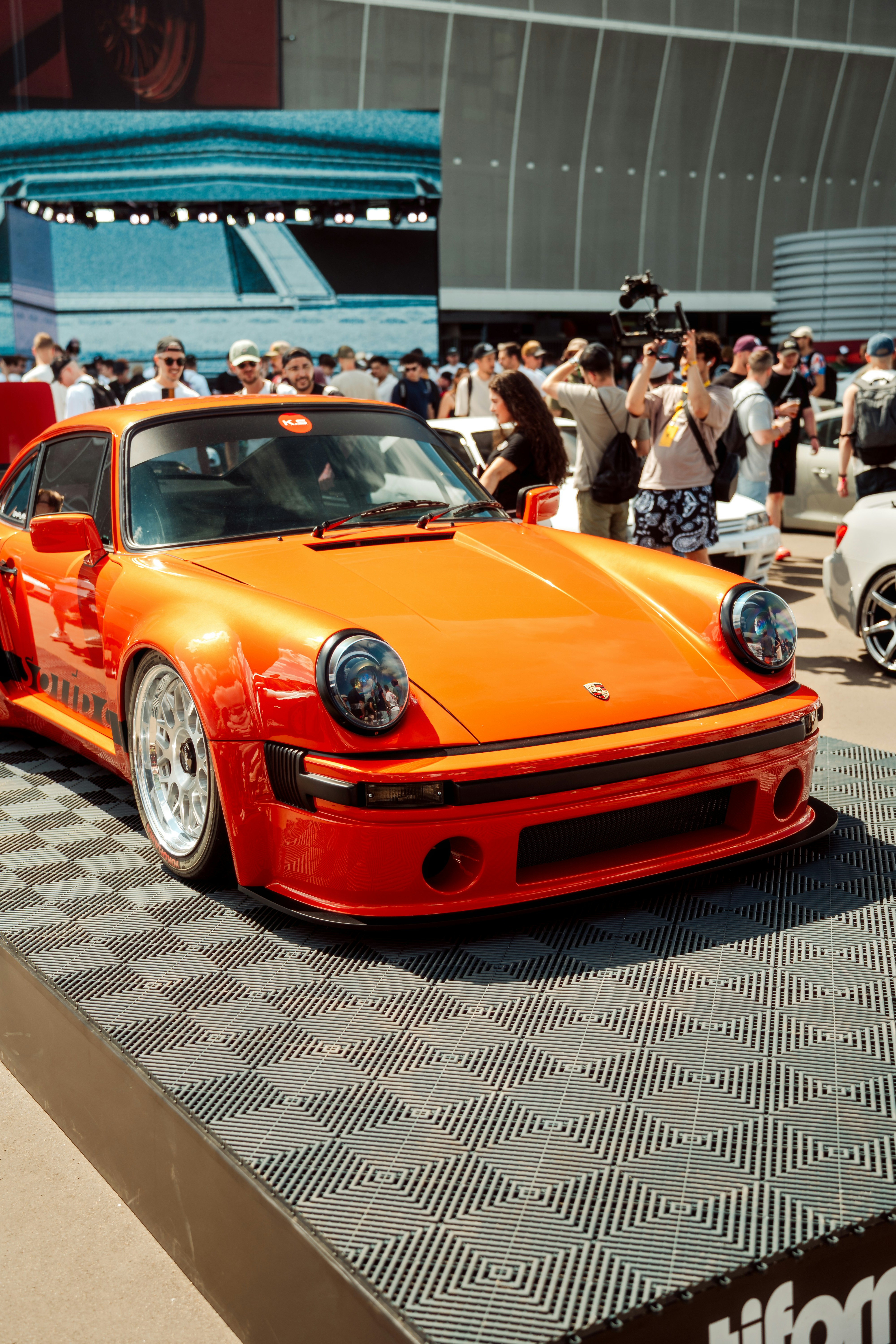 A vibrant orange porsche car show displayed.