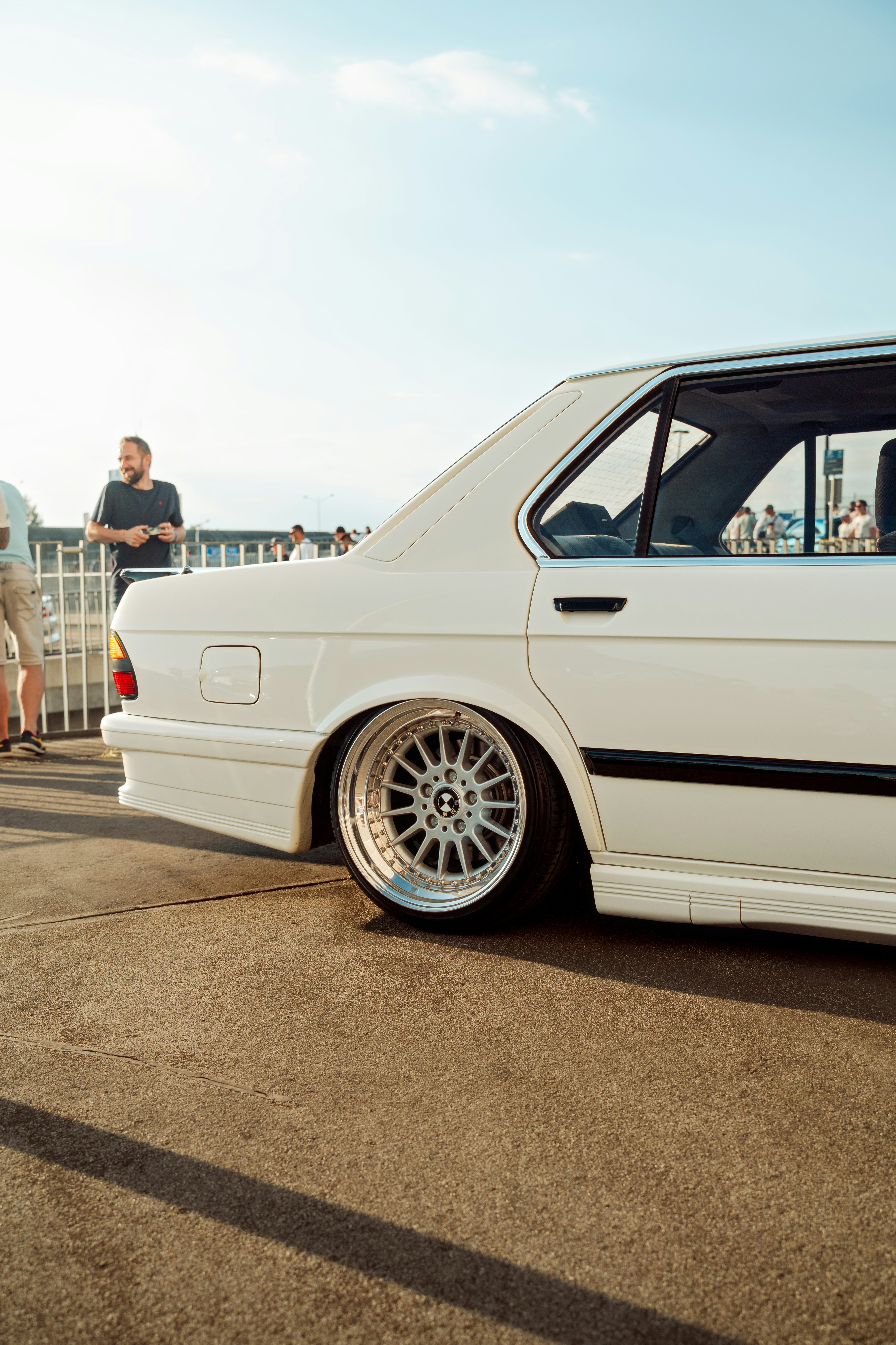 A white classic car parked in the sunshine.