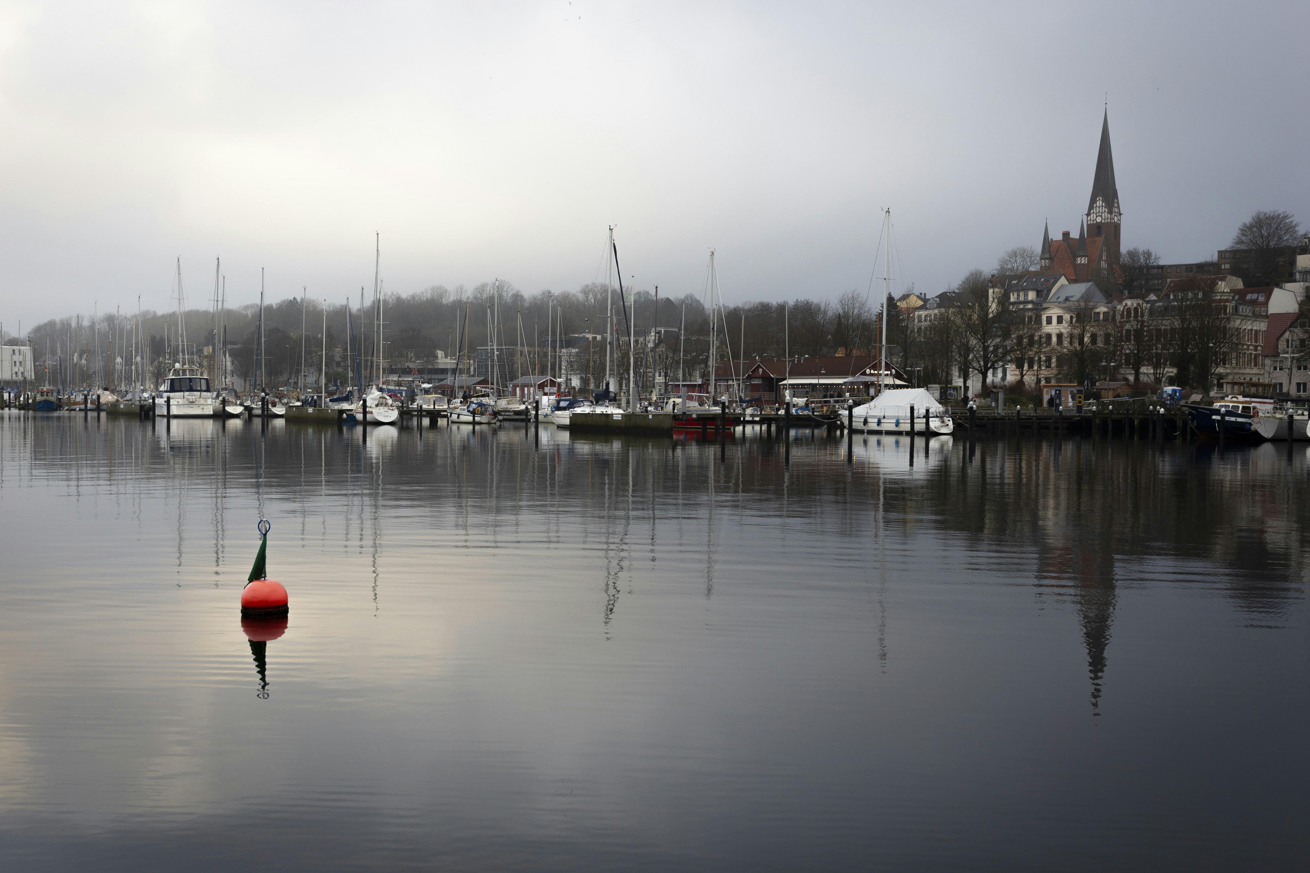 Boats and buildings reflected in calm water.