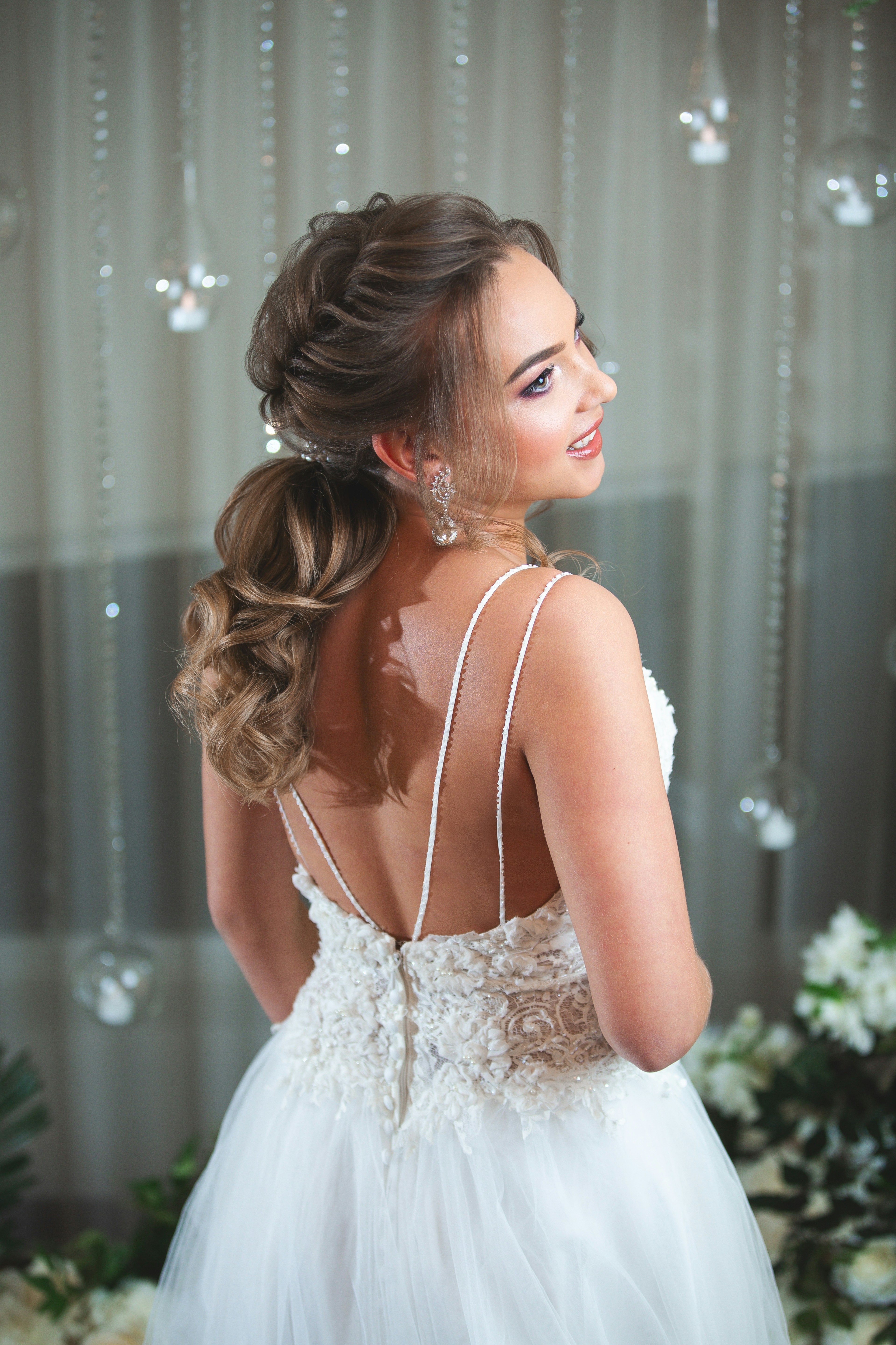 Bride in a lace gown looking away with a smile.