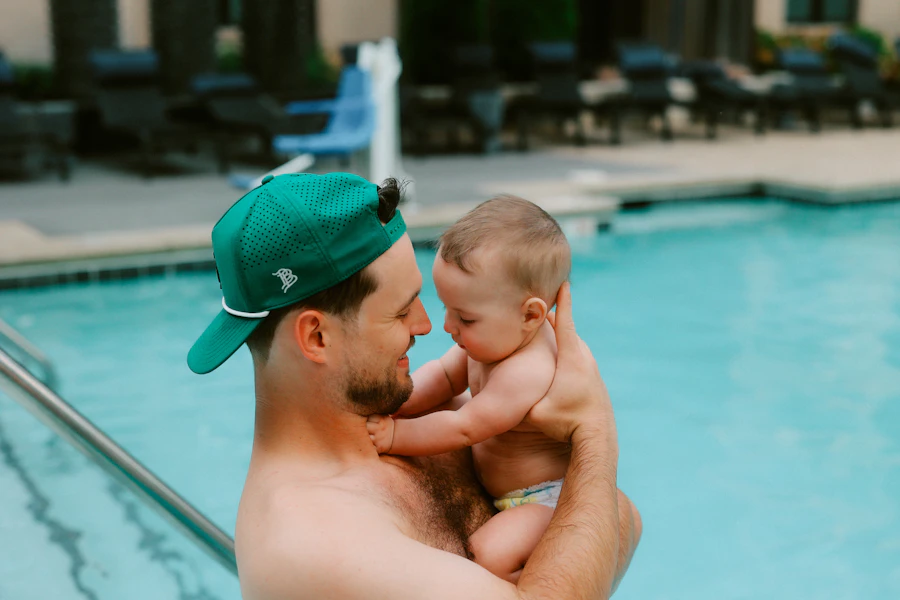 Père avec bébé au bord de la piscine