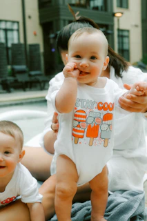 Babies are smiling while wearing "stay cool" shirts.