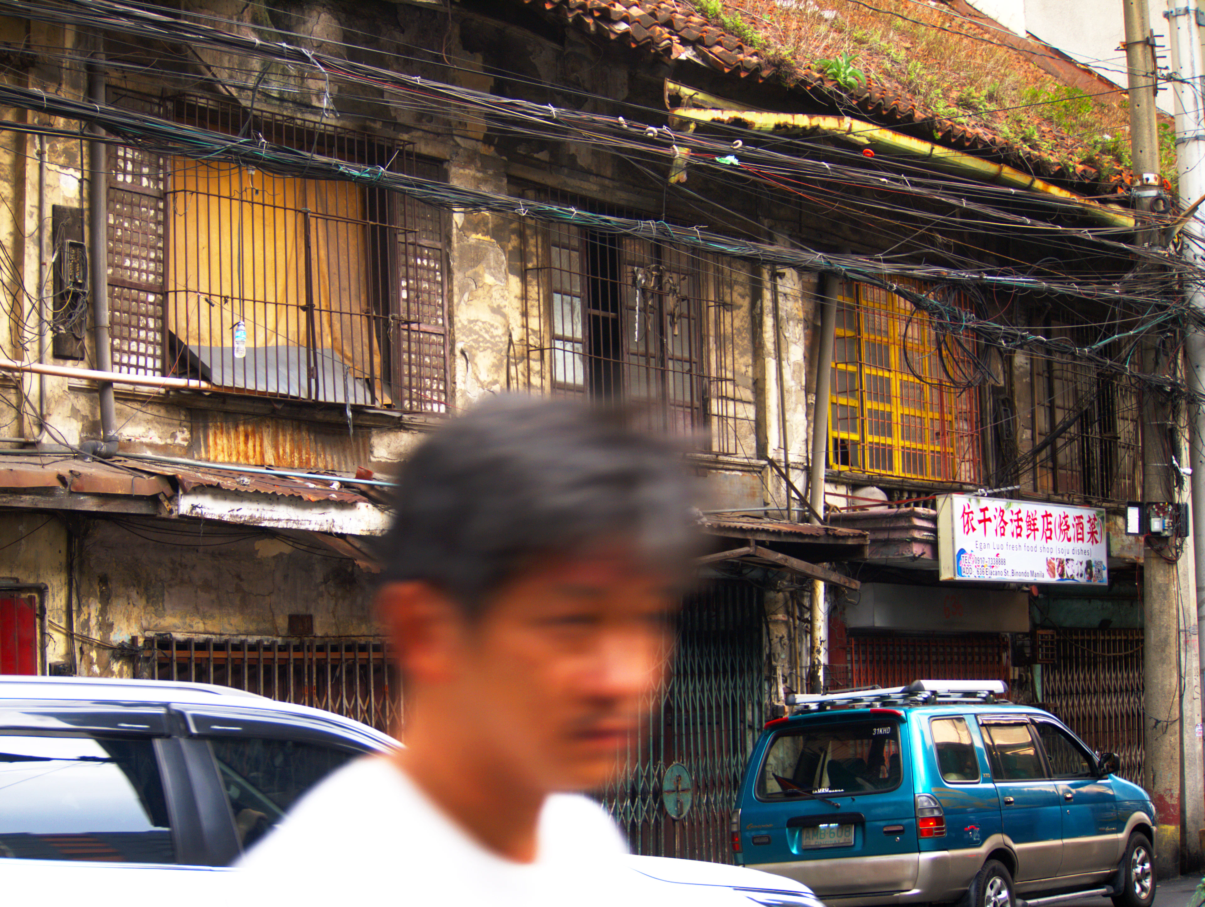 A street in Binondo, Manila, old shophouse balconies above jeepneys and market stalls