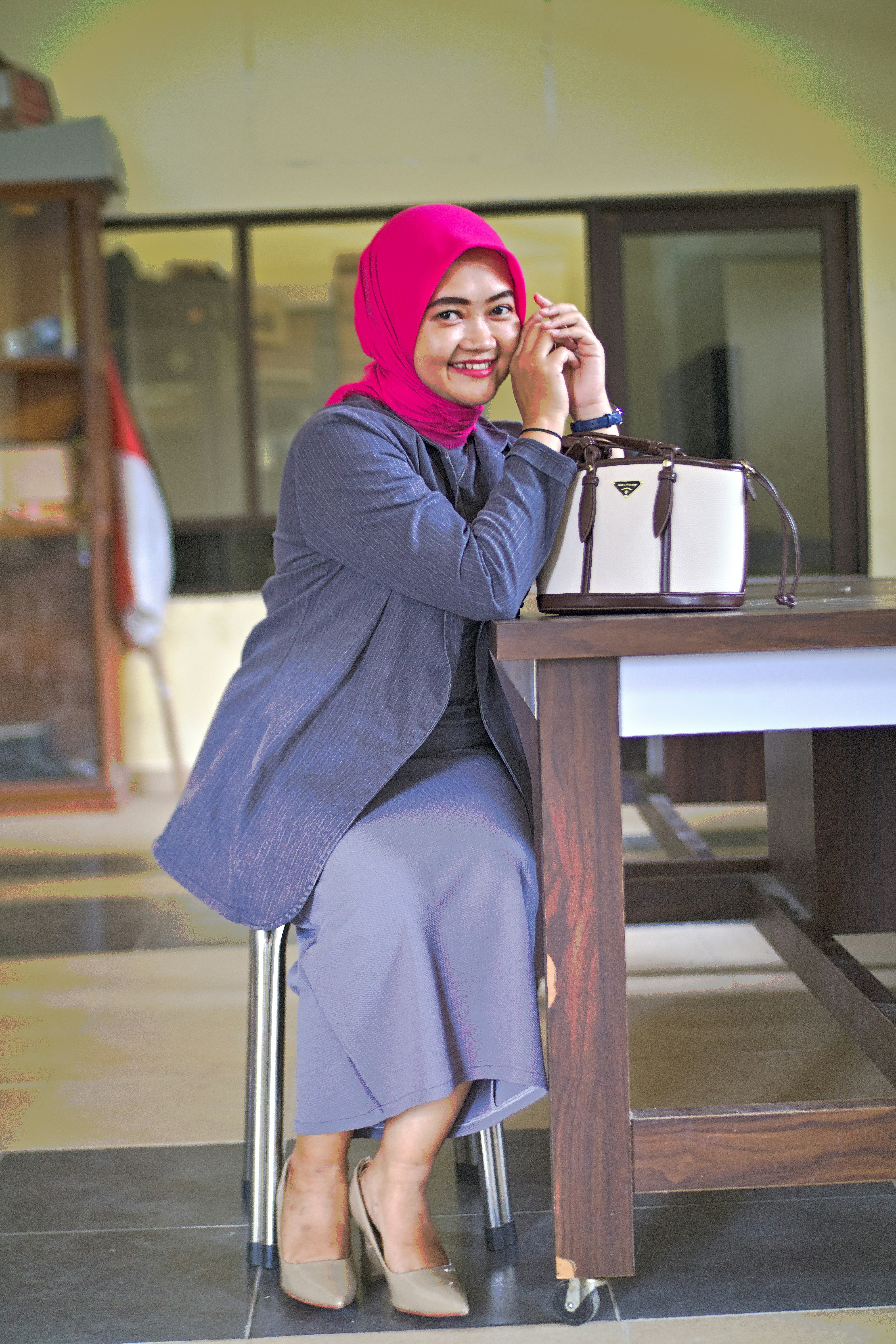 A woman smiles while seated next to a bag.