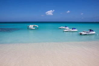 Jet skis float in crystal-clear turquoise water.