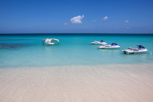 Jet skis float in crystal-clear turquoise water.