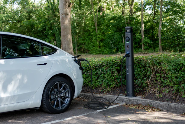 White electric car plugged in at a charging station.