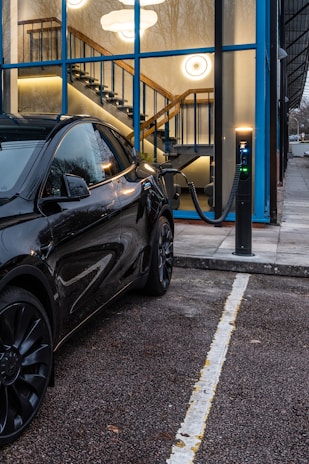A black tesla is charging at a station.