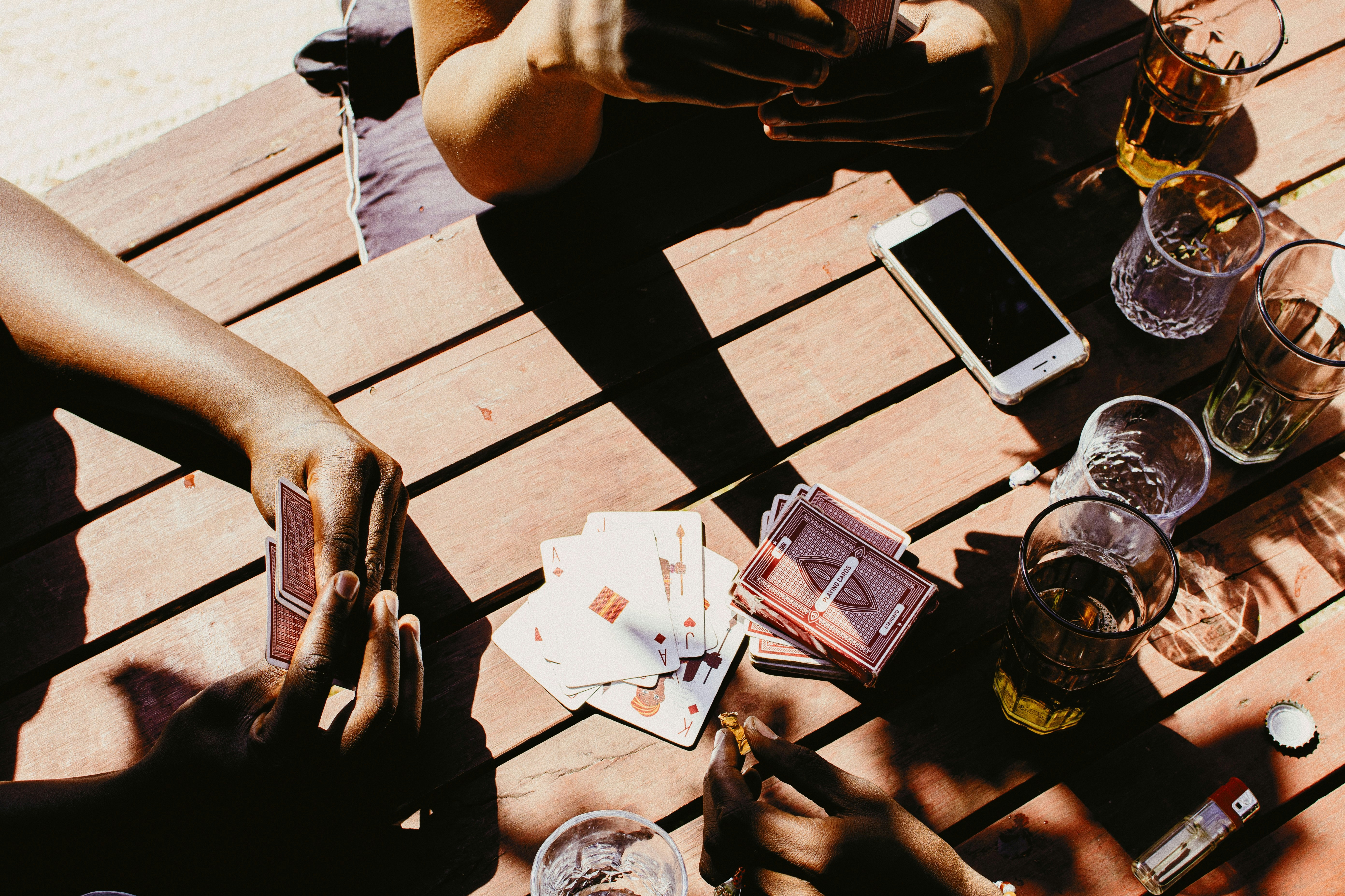People playing cards and enjoying drinks outdoors.