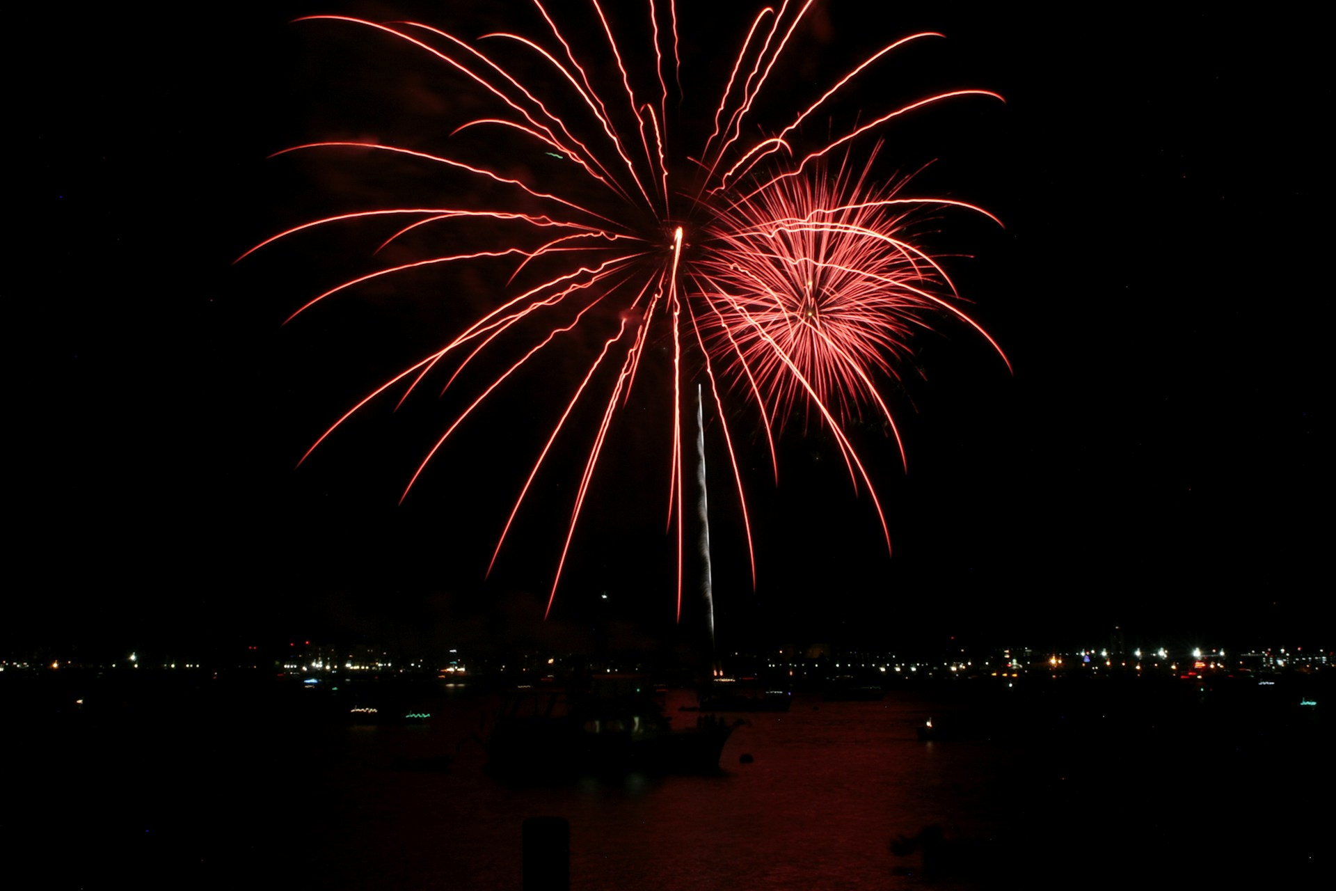 Red fireworks explode in the night sky.