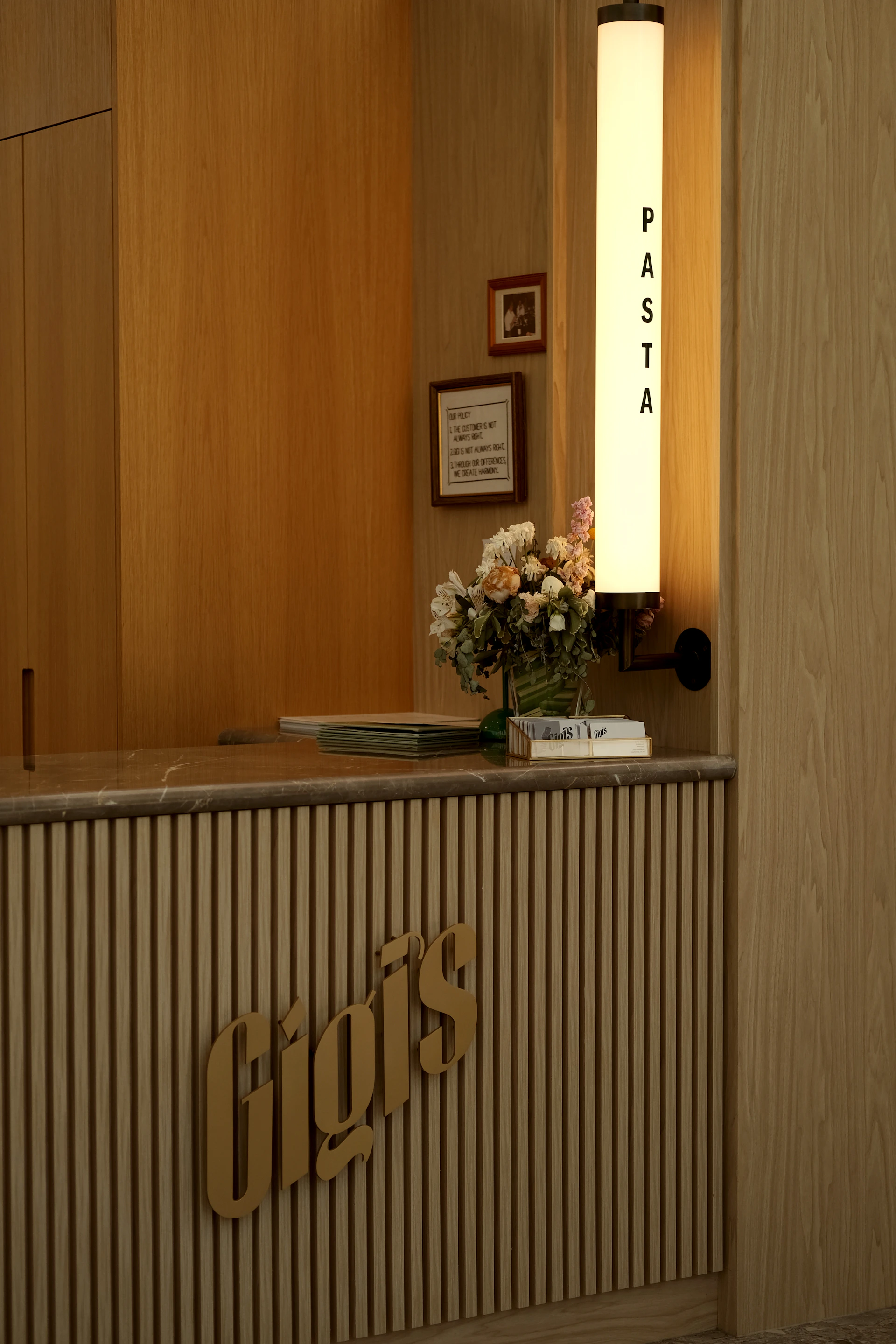 A restaurant's welcoming reception with a pasta sign.