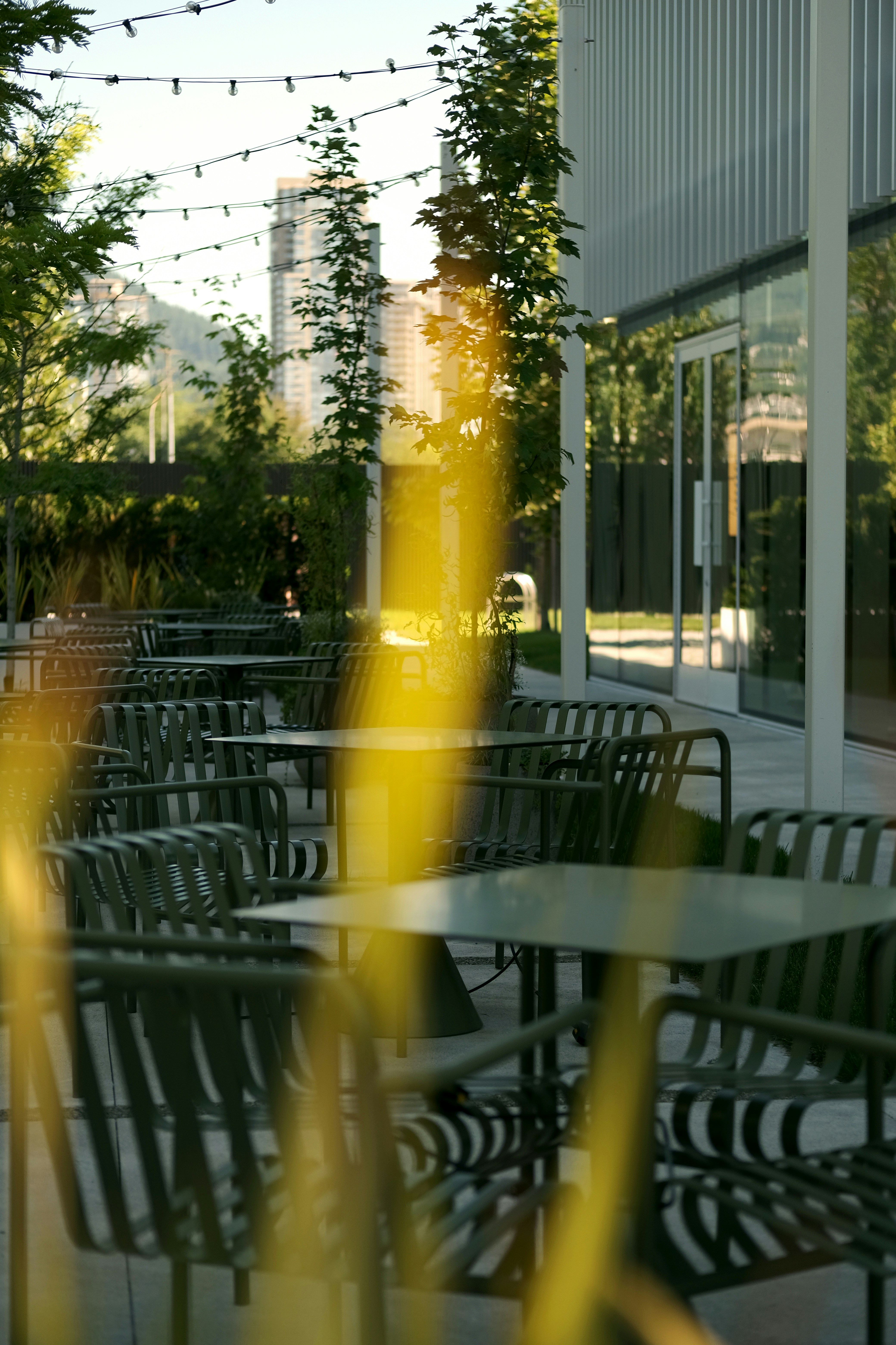 Outdoor seating area with string lights and a city backdrop.