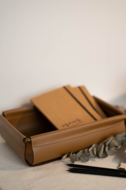 Leather tray with notebooks and pencils.