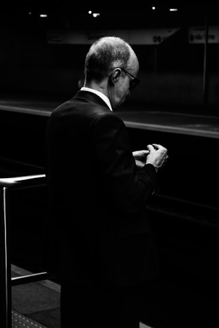 A businessman checks his watch at a train platform.