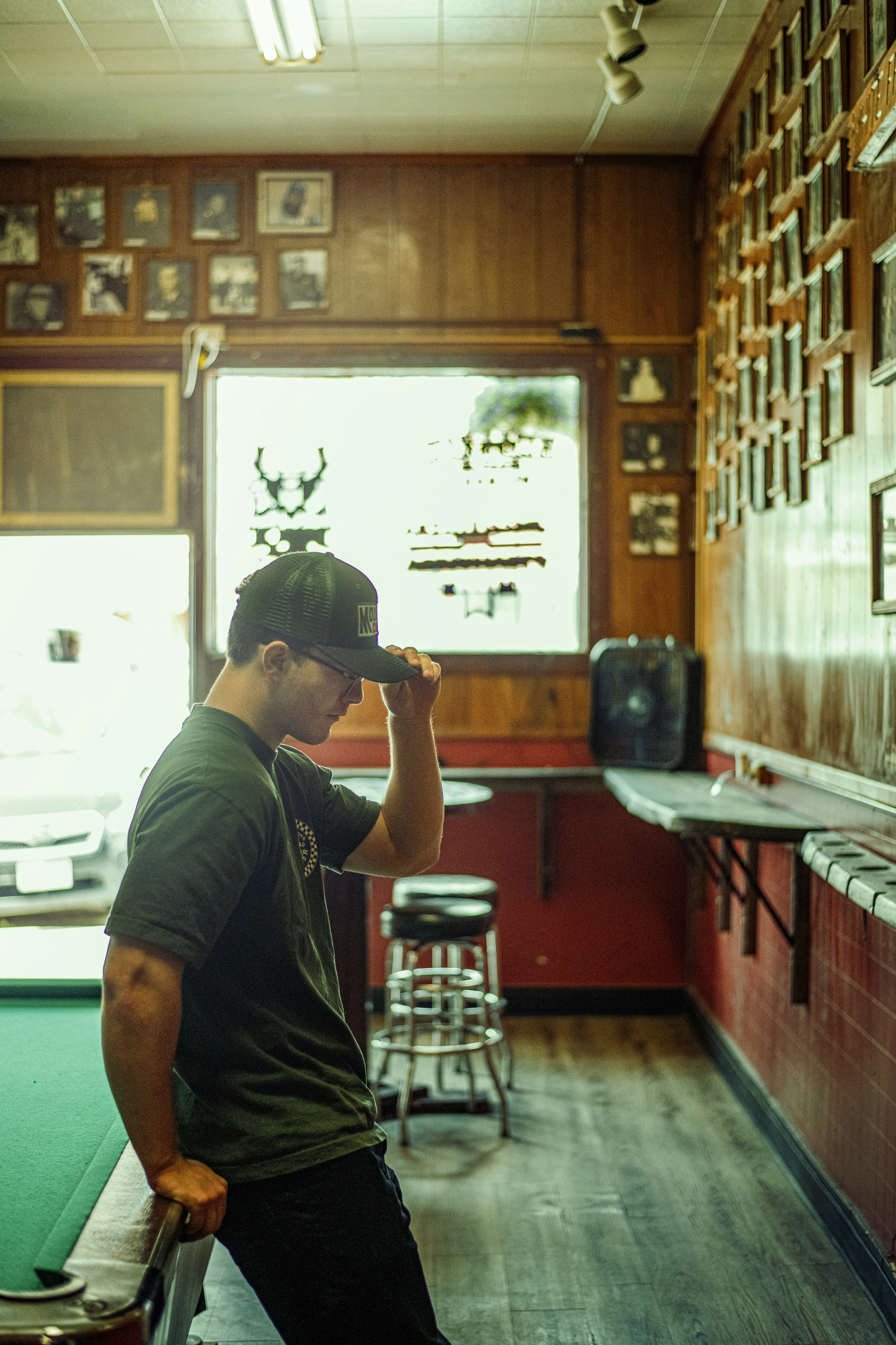 Man in a hat at a dimly lit pool hall.