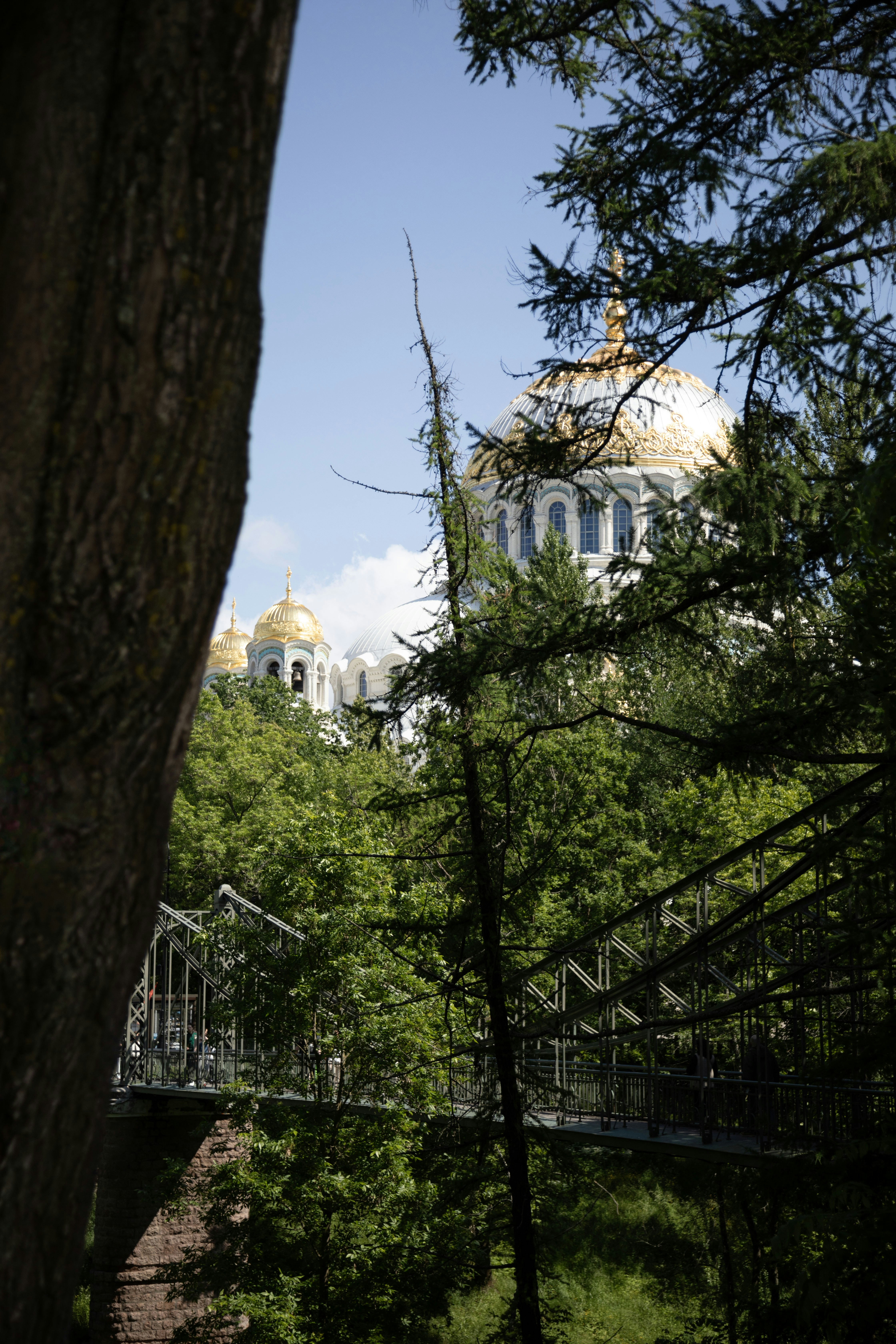 Church domes peek through trees and over a bridge.