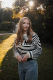 A young woman poses in a park.