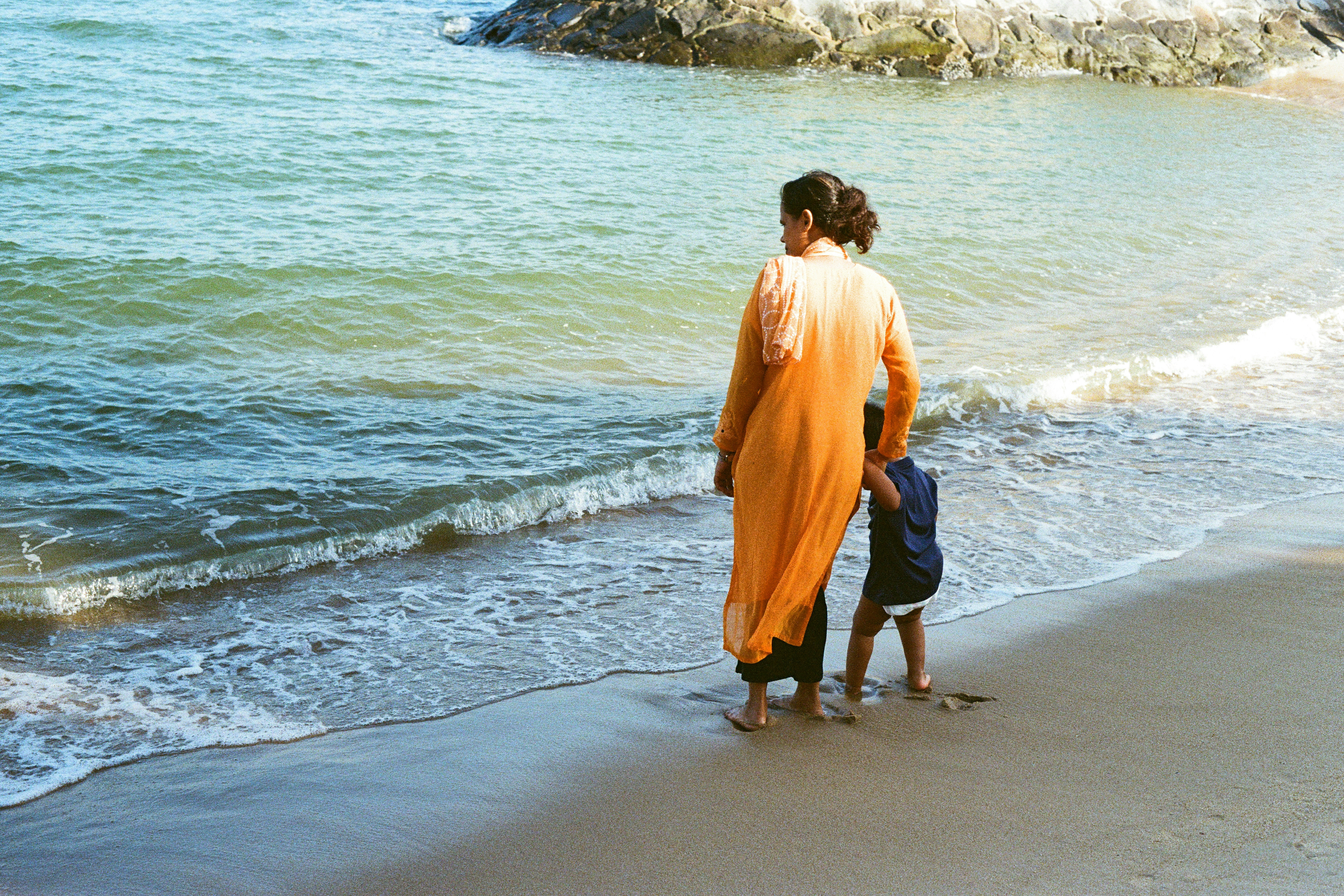 Seorang wanita dan anak berdiri di pantai.