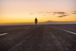 A person walks alone on a desert road.