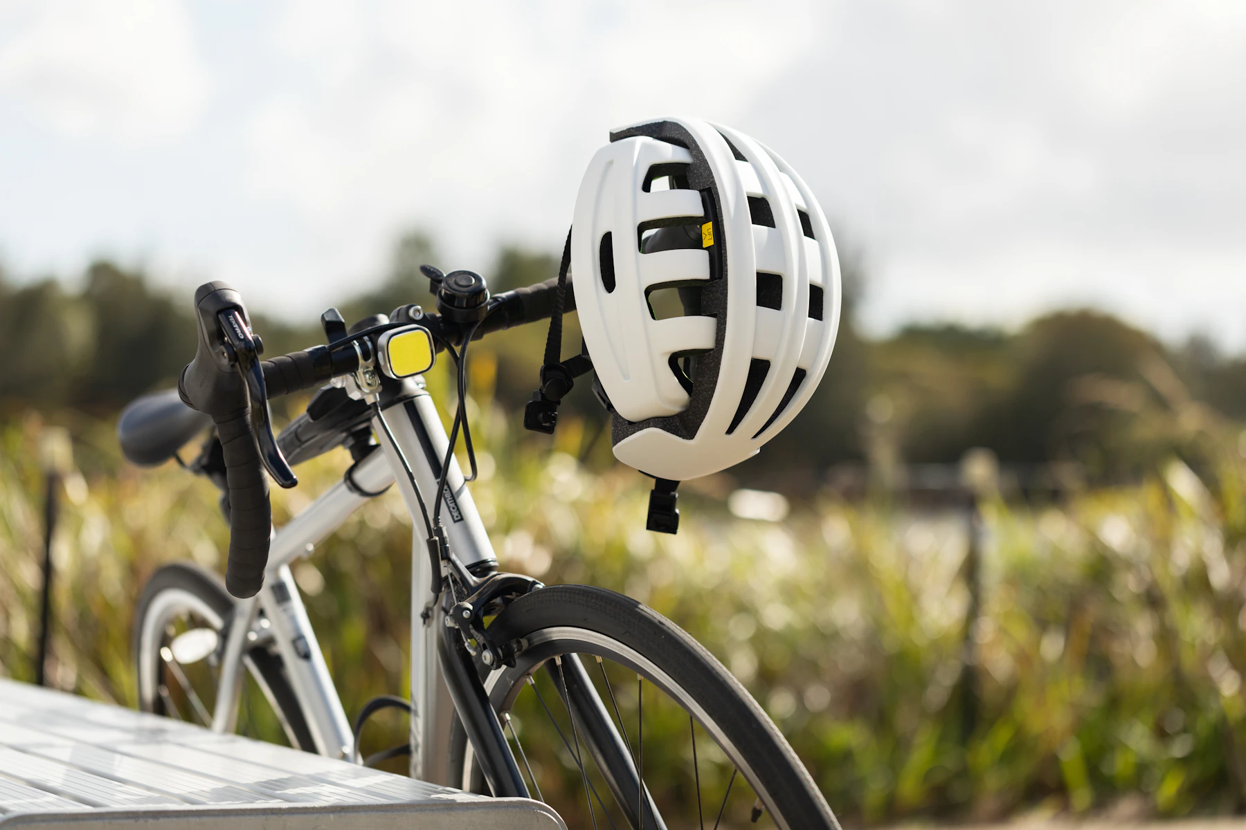 White cycling helmet resting on the handlebar of a road bicycle