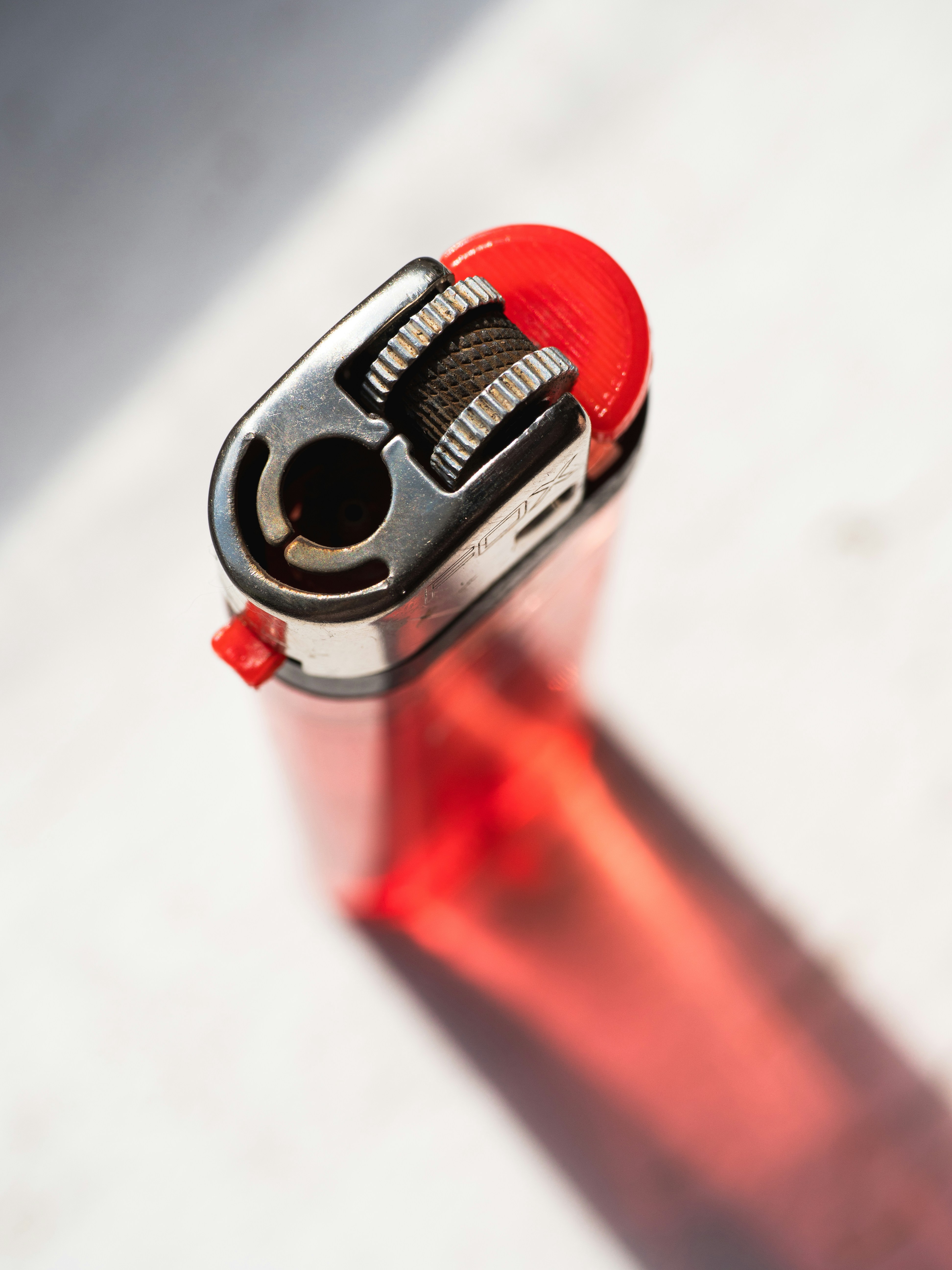 Hier ist eine Bildunterschrift: Ein rotes Feuerzeug wirft einen Schatten.