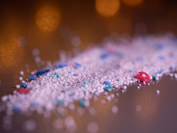 Laundry detergent granules are piled on a surface.