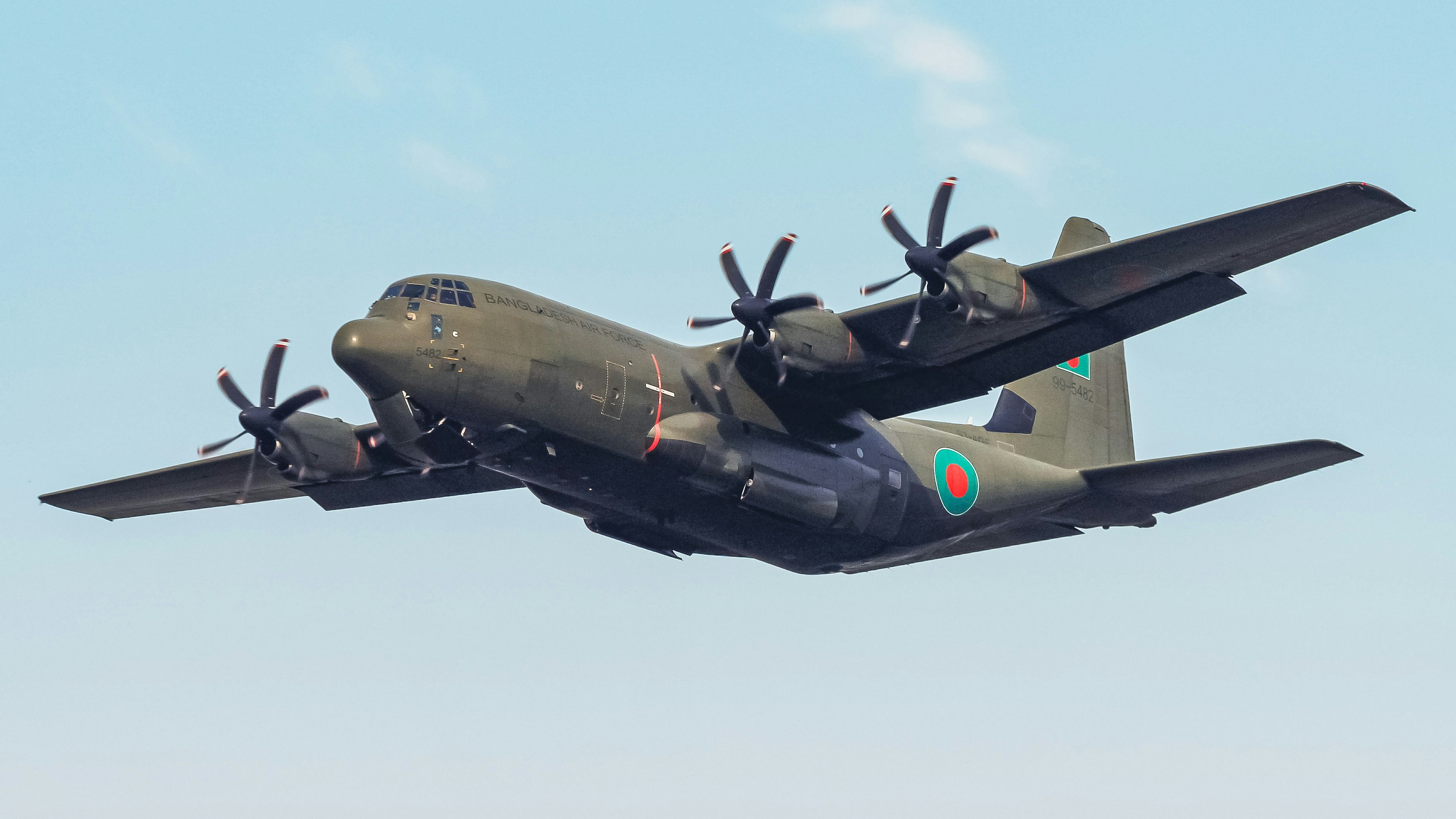 A military airplane soars through the sky.