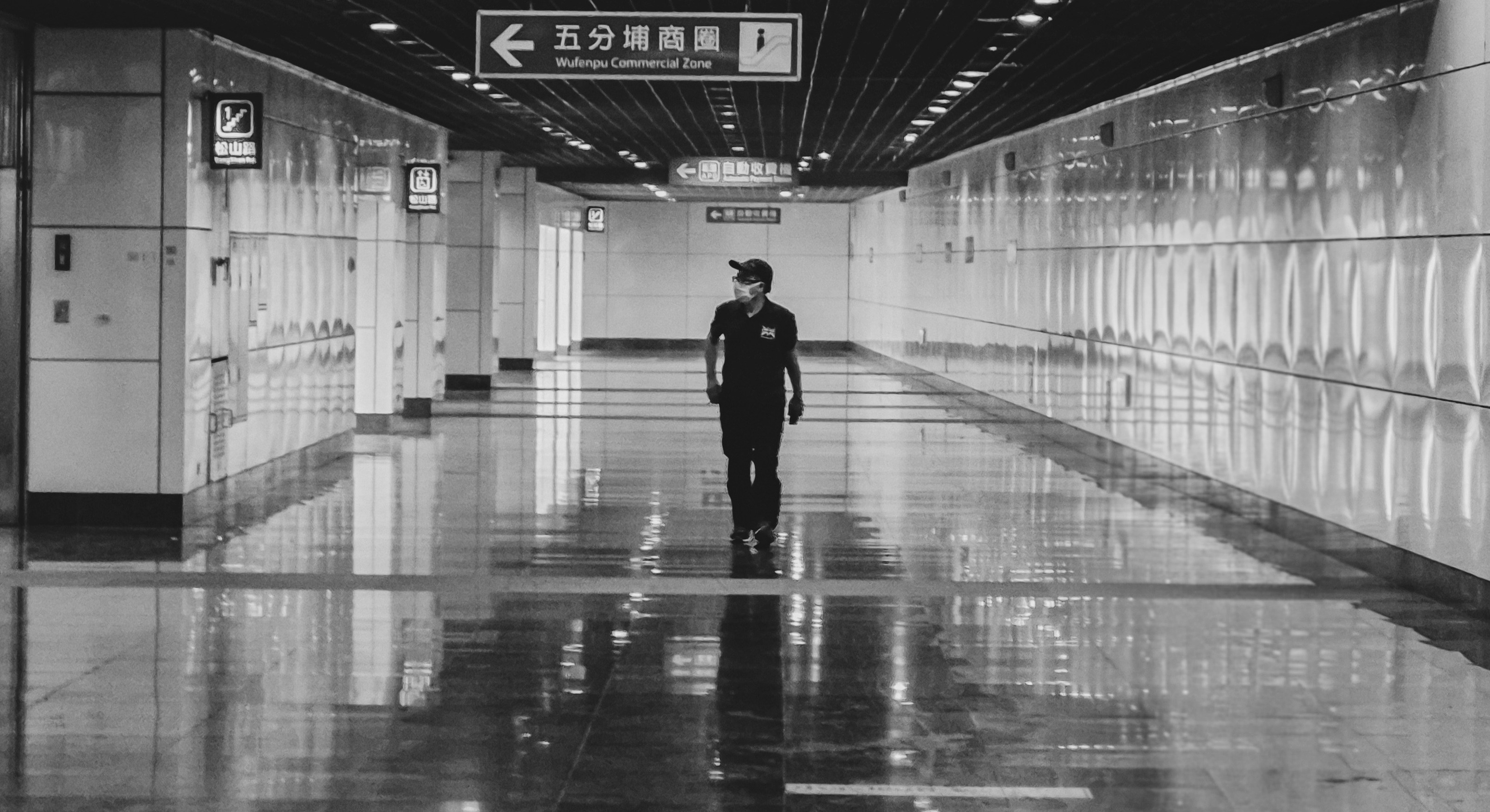 A person walks in an empty, spacious subway
