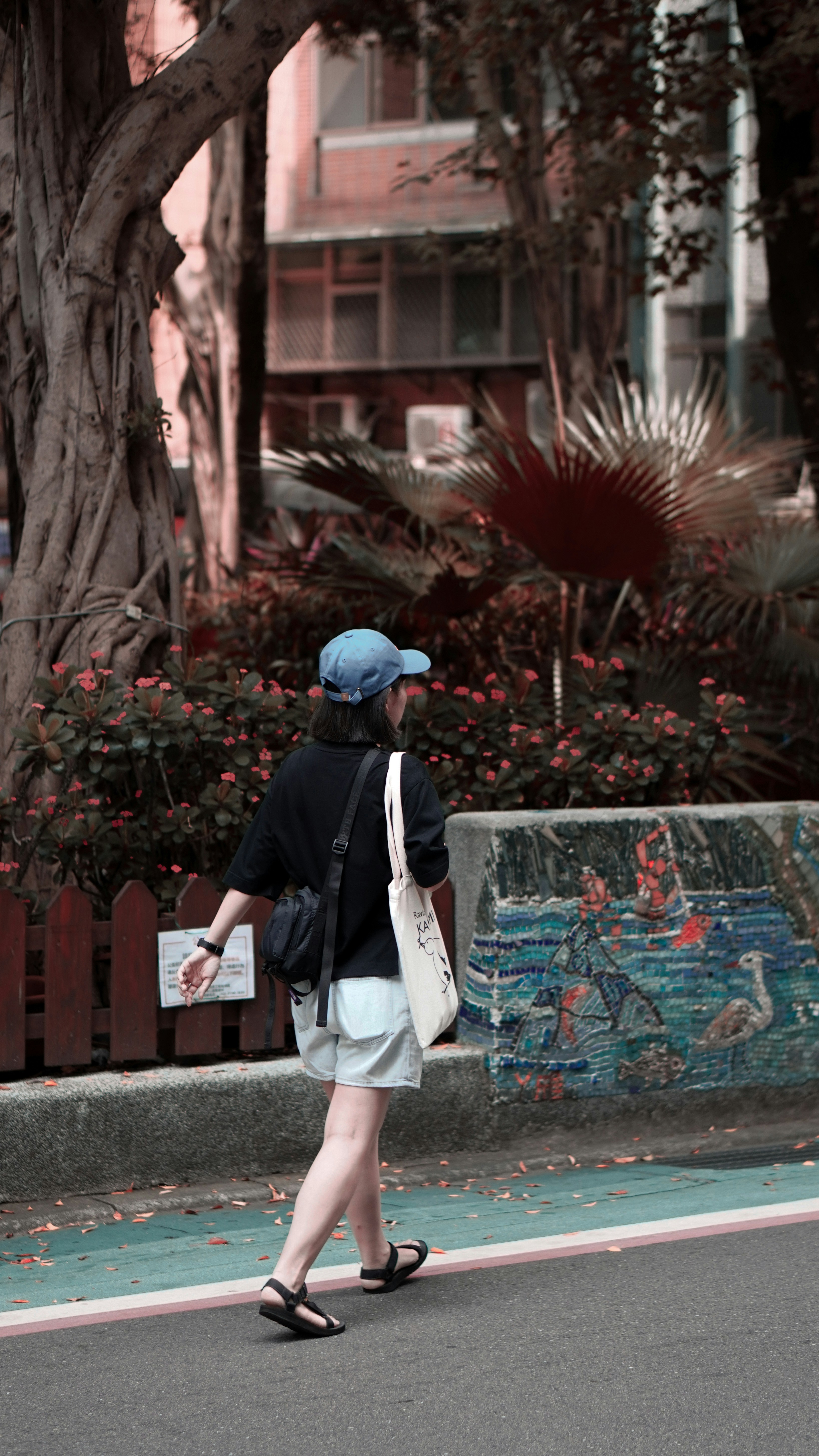 A woman walks along a road with a mural