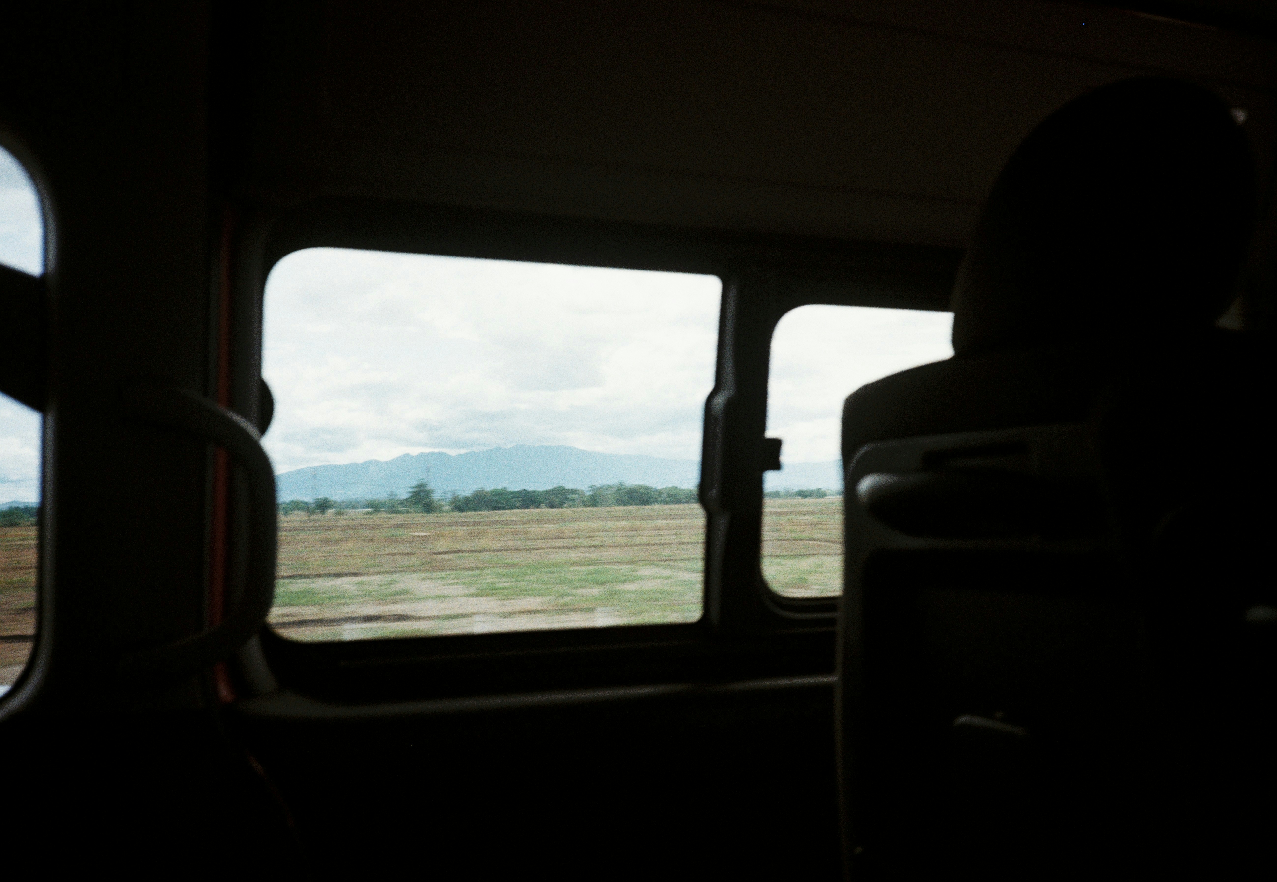 Inside a bus, looking at a distant landscape.