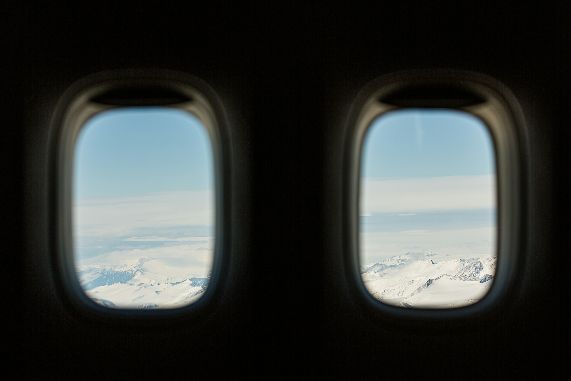 Snowy mountain landscape seen through two airplane windows