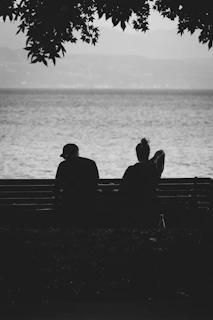 Couple sits on a bench, gazing at the sea.