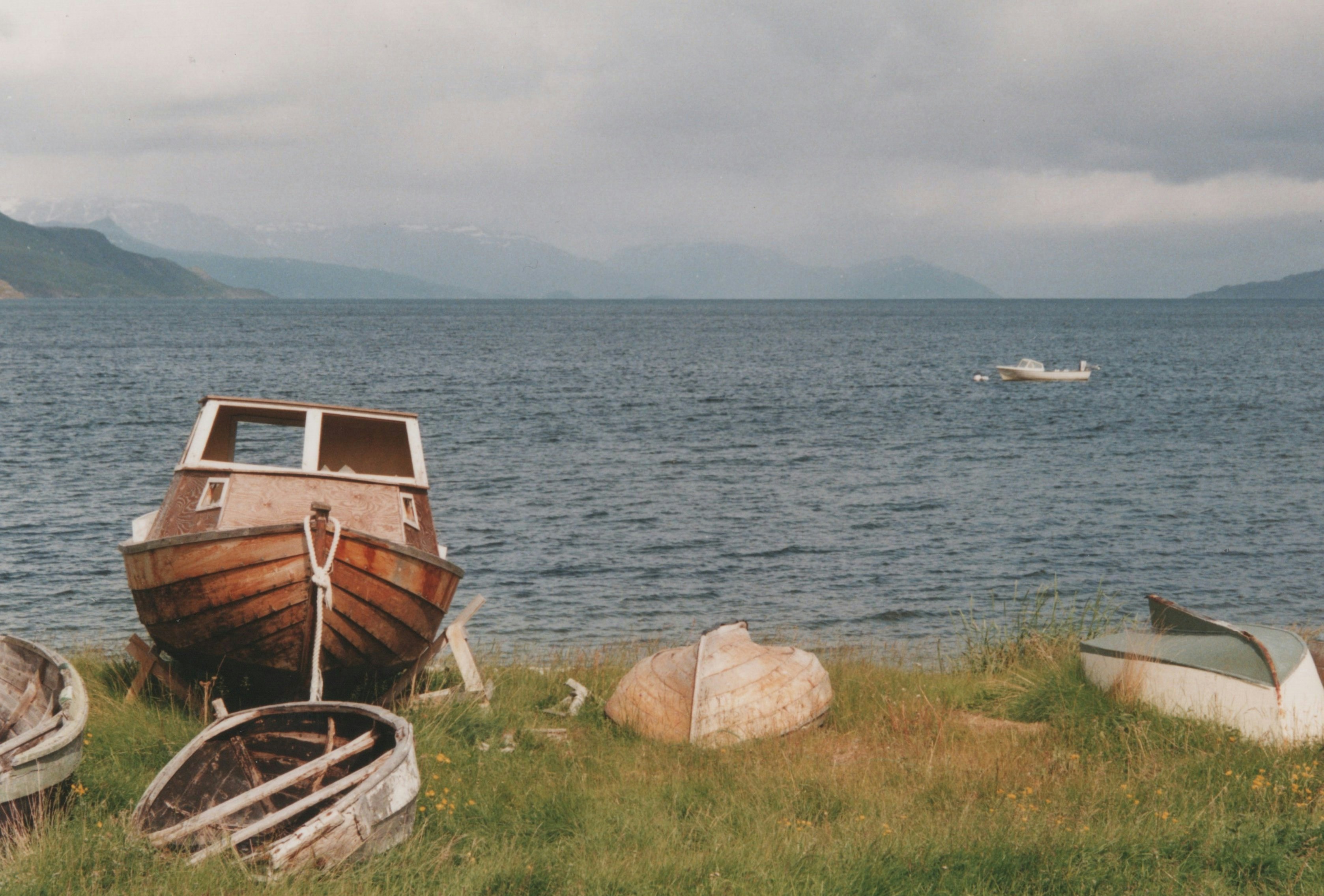 Boats resting on a shore, with a lake in the background.