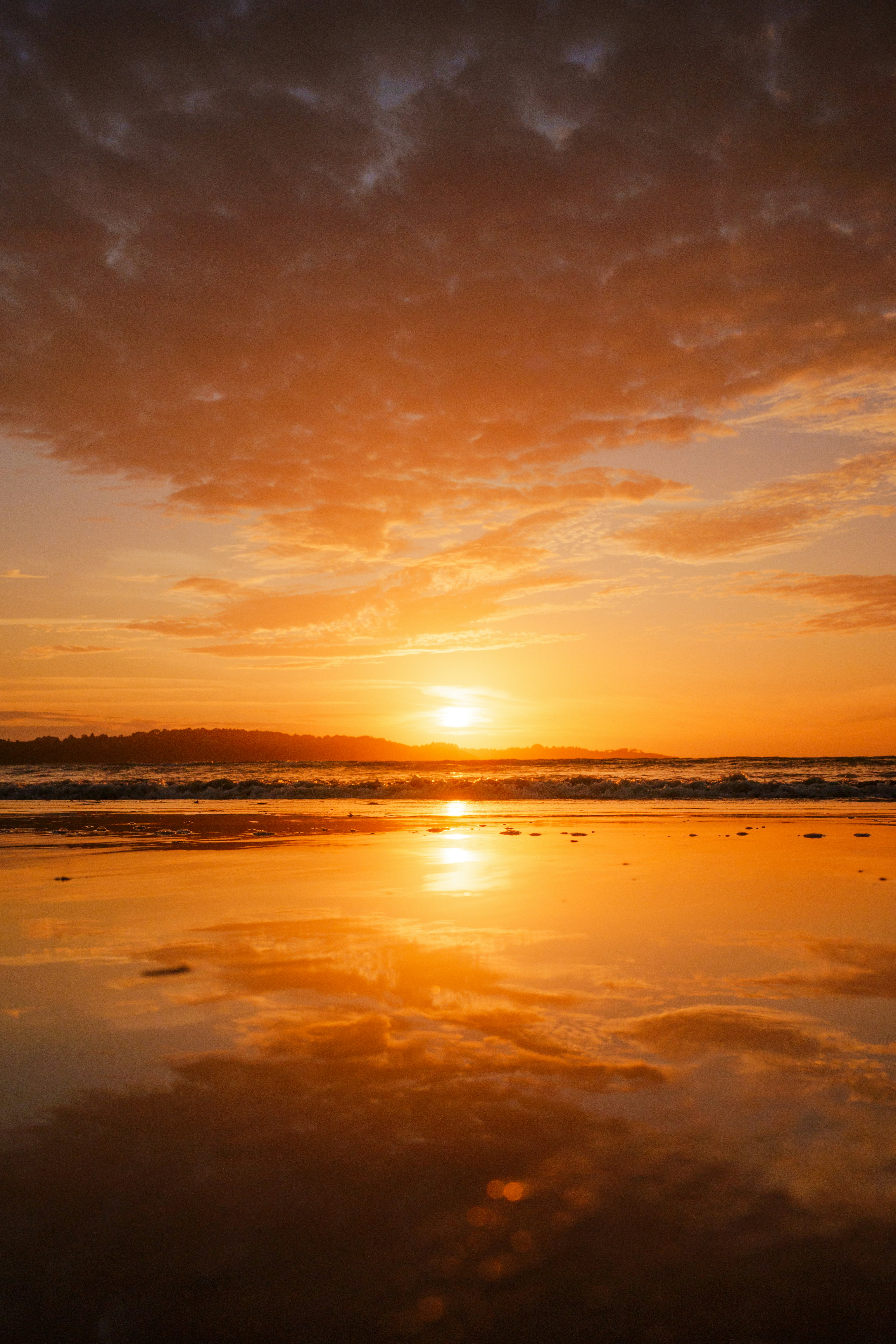Sunset casts an orange glow over the beach.