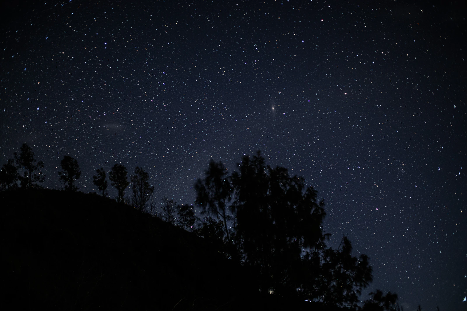 A night sky filled with countless stars over dark terrain