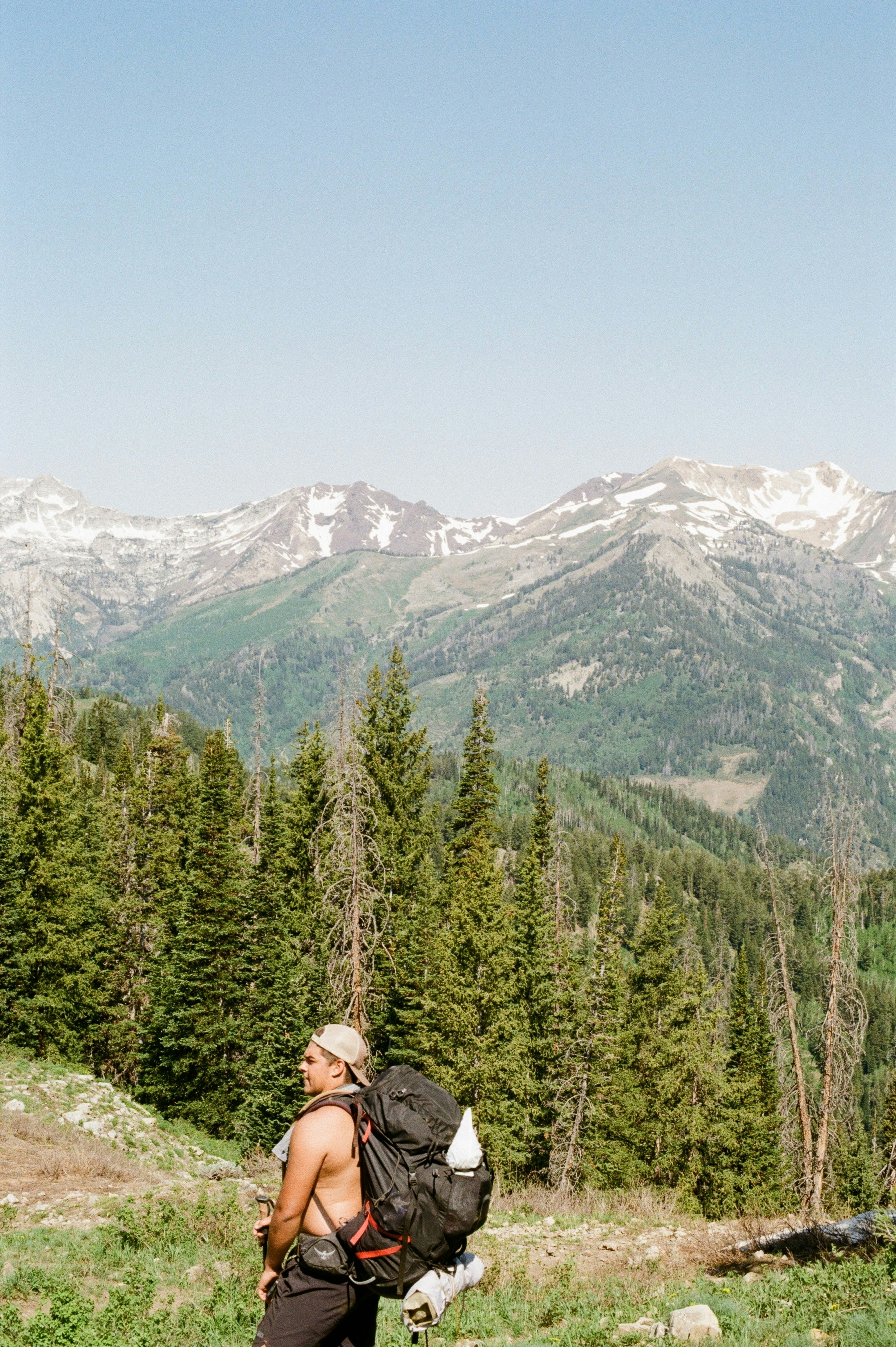 Hiker stands facing the mountain vista with backpack