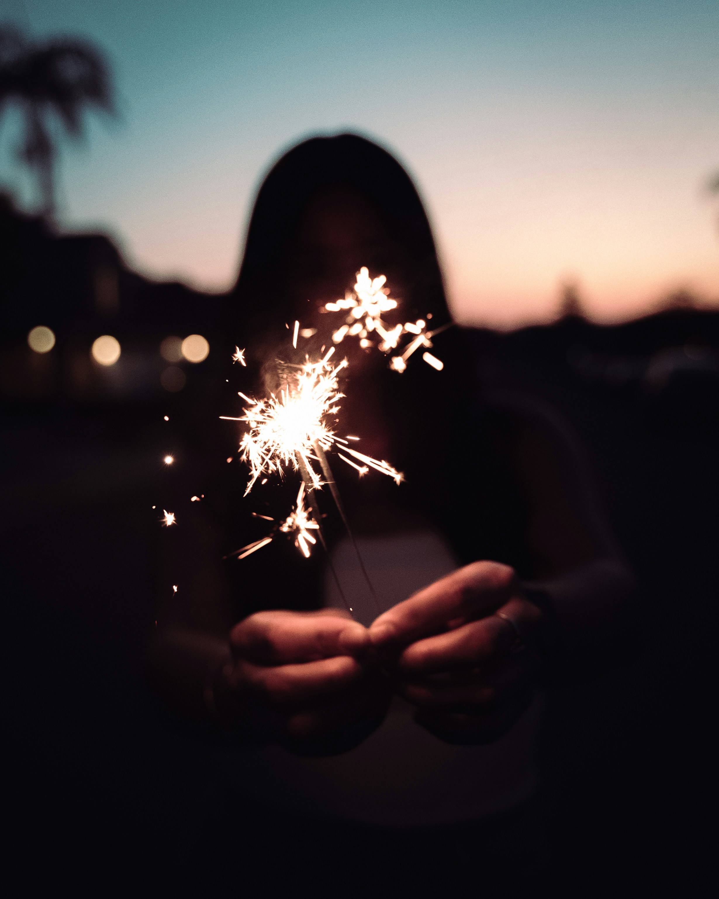 A person holds a sparkler in the twilight.