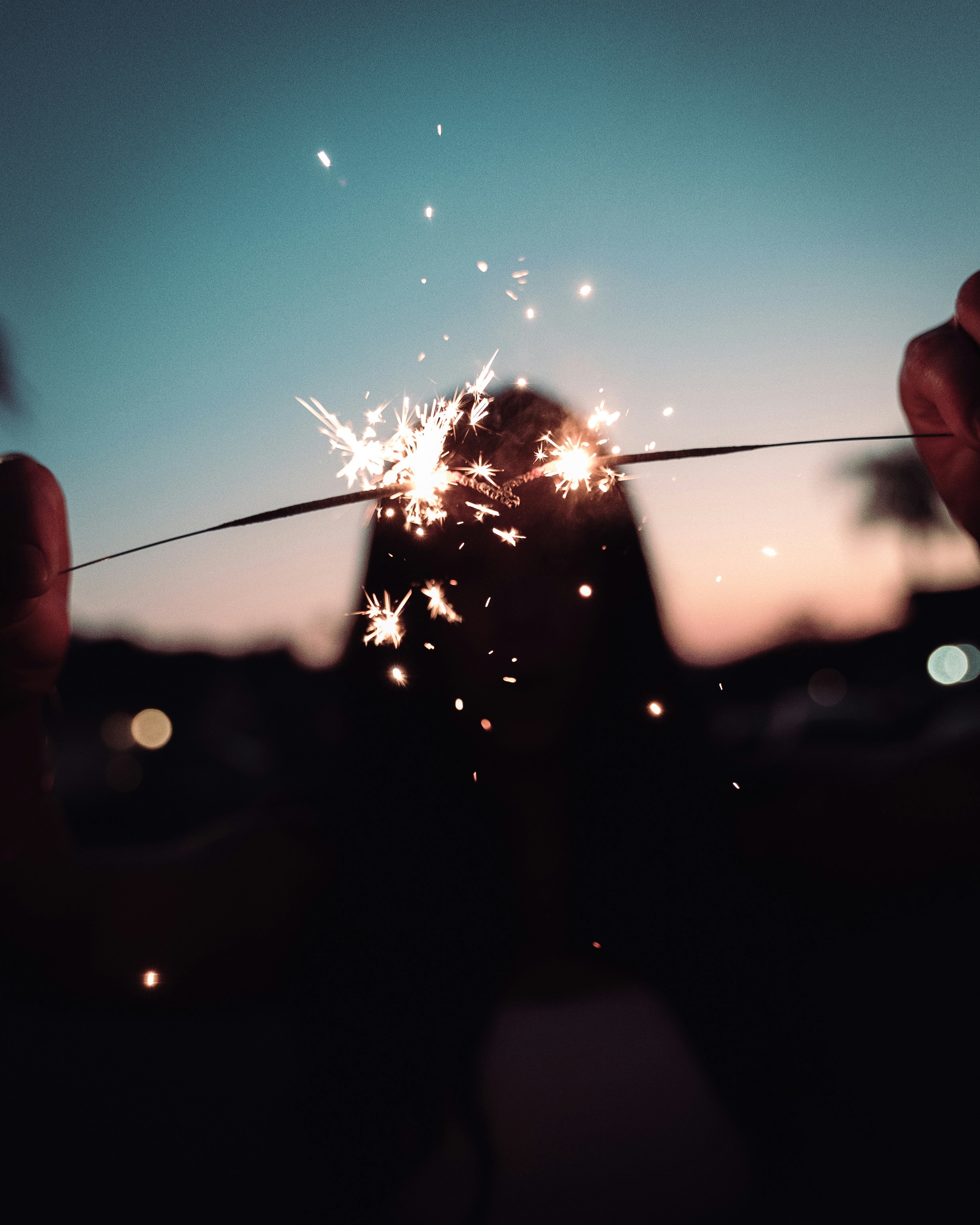 Sparks fly from a sparkler at sunset.