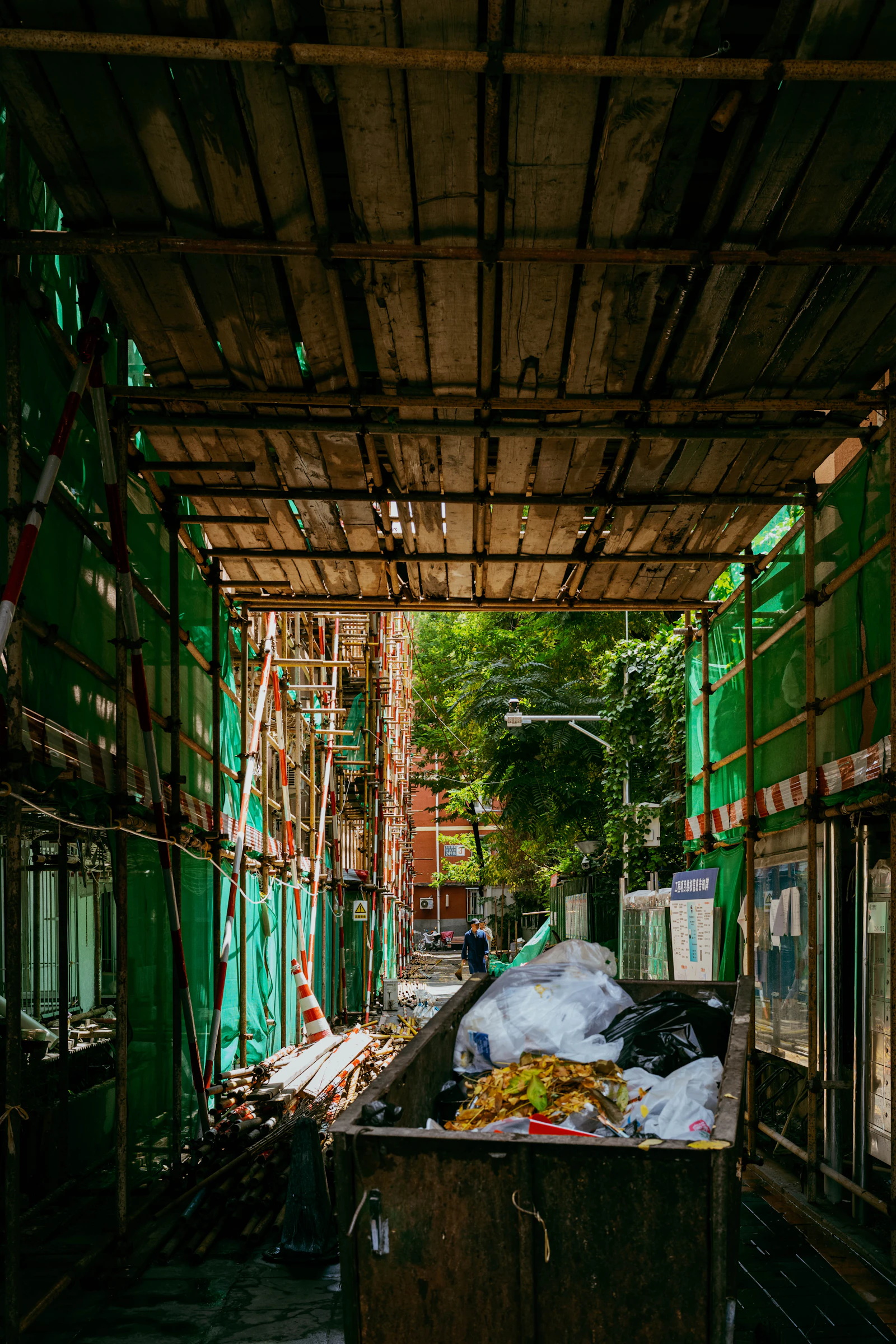 Dumpster staged in an alley beside a work site