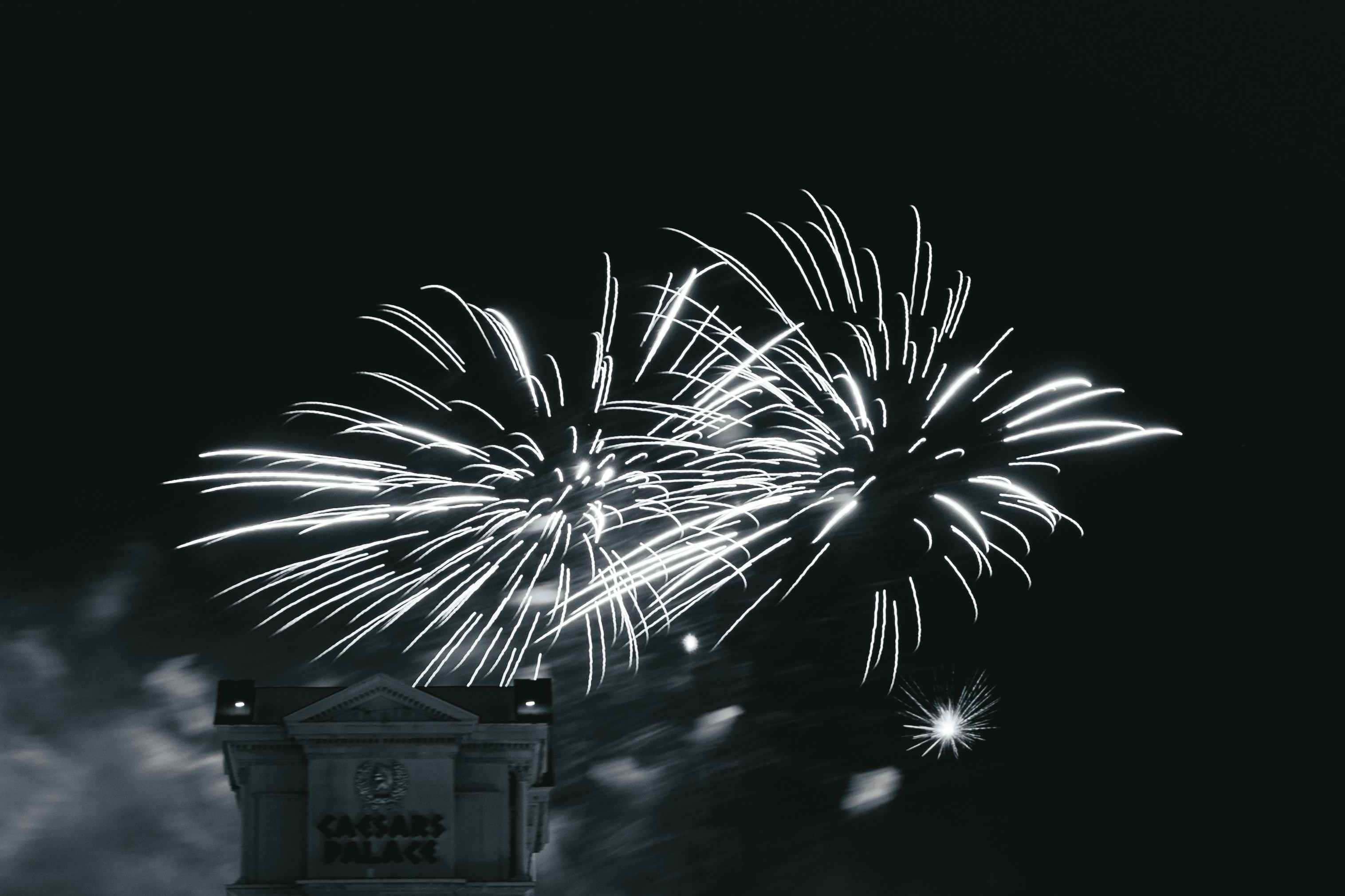 Fireworks explode above a building at night.