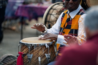 A musician plays a drum at an outdoor event.